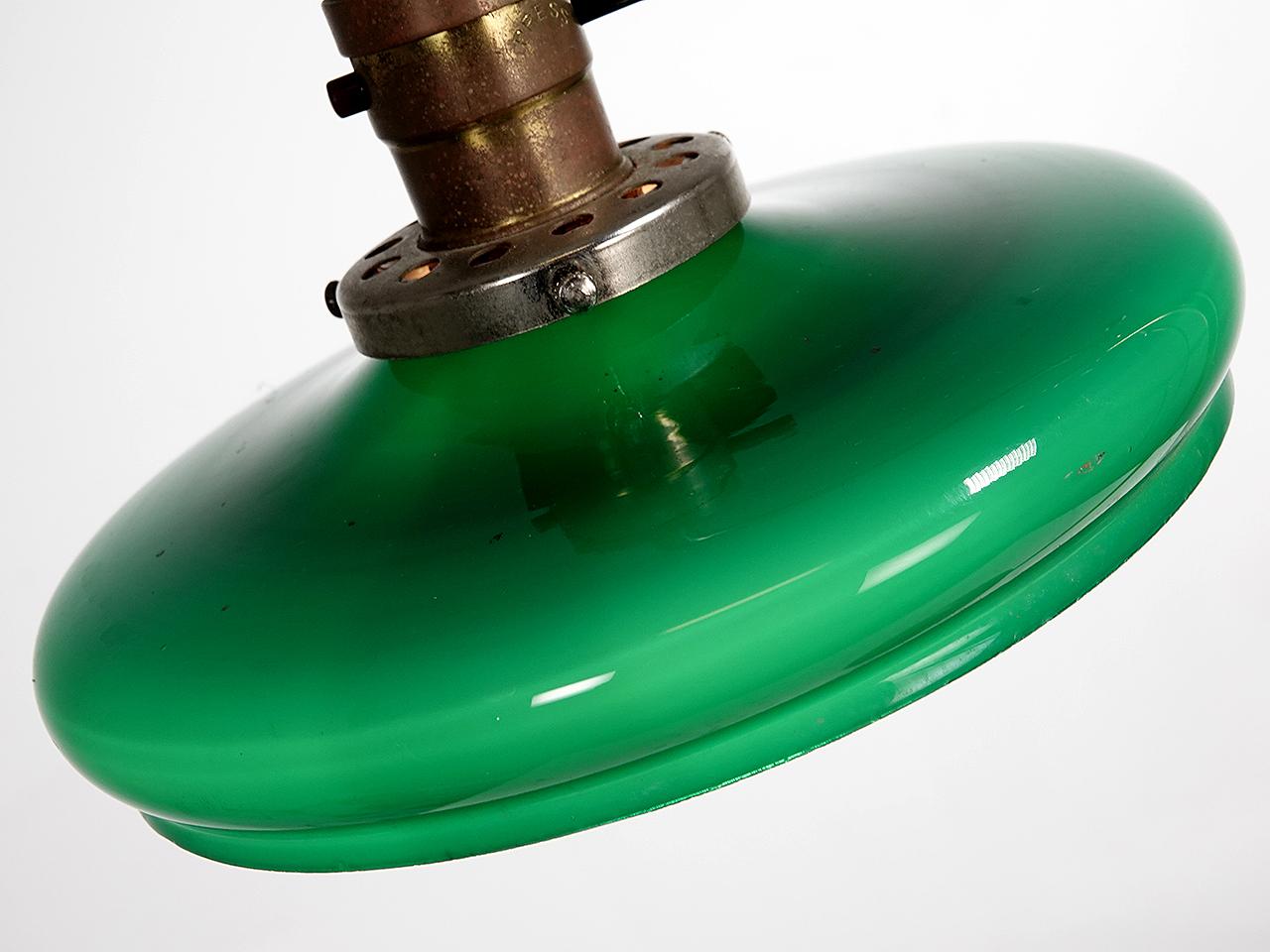 This is a really clean and simple brass desk lamp with a rare unique shade. The shade is an emerald over white sandwich glass that has a nice flattened profile giving the lamp a look all its own. The shade and horizontal arm can turn and ride up or