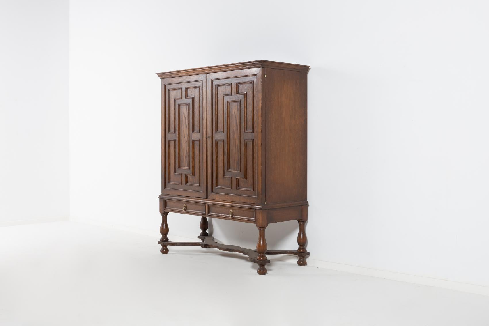 Scandinavian Modern cabinet by Swedish icon Axel Einar Hjorth for Nordiska Kompaniet, produced in 1930s. The piece is made of stained oak, equipped with 2 drawers and 2 doors. Inside has a space for wine bottles, wine glass holders attached to
