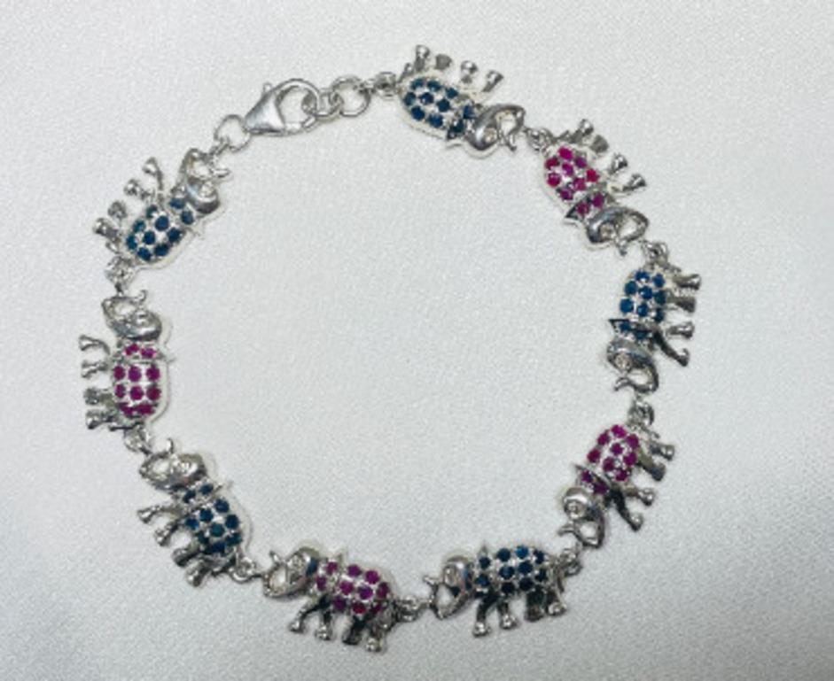 Exclusiva pulsera de zafiro azul y rubí en forma de elefante, de plata de ley, que exhibe un zafiro azul natural infinitamente brillante y un rubí de 3,56 quilates. Mide 7.25 pulgadas de largo. 
El Zafiro Azul y el Rubí estimulan la concentración y