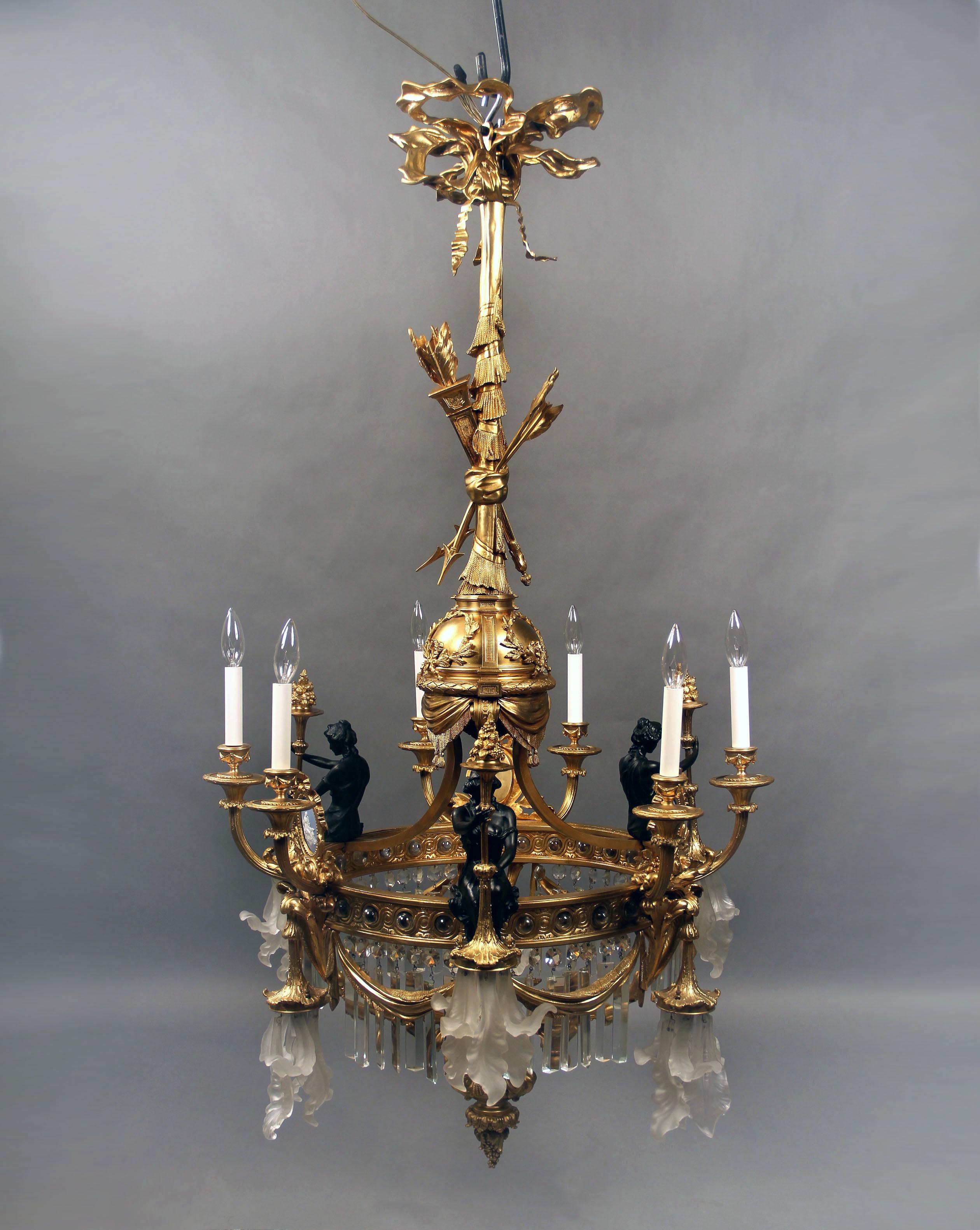 A unique late 19th-early 20th century gilt and patina bronze, crystal and wedgwood porcelain thirteen-light chandelier.

Three scantily clad dressed maidens sit atop the perimeter of the chandelier, centered by three Wedgwood plaques. The top