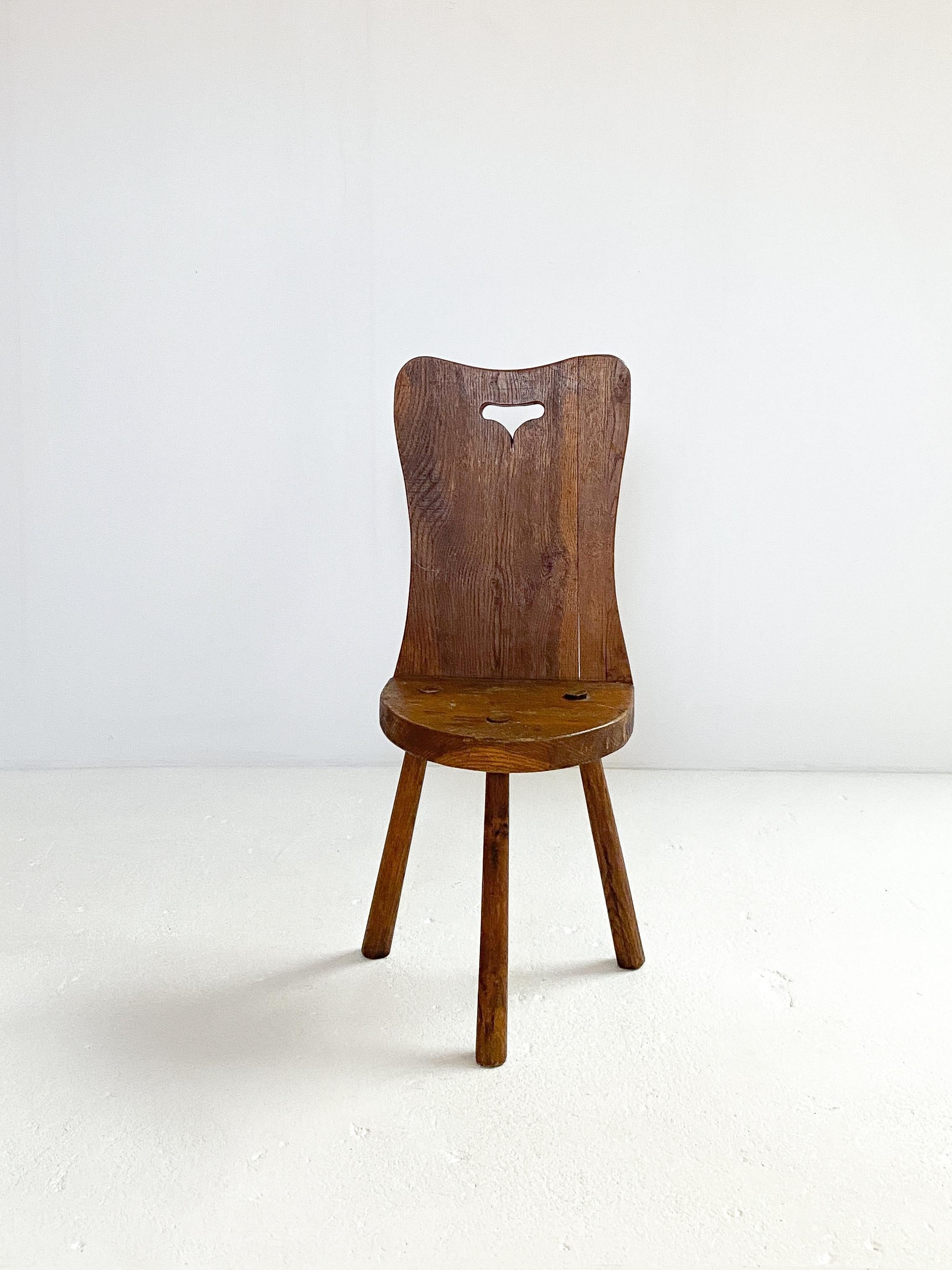 Brutalistischer dreibeiniger Holzhocker aus Frankreich, ca. 1950er Jahre. 
Massiver und klobiger Sitz mit stabilen Beinen. Dieser Hocker hat eine beeindruckende, hart geformte Rückenlehne mit einer halbmondförmigen Sitzfläche mit großem Charakter