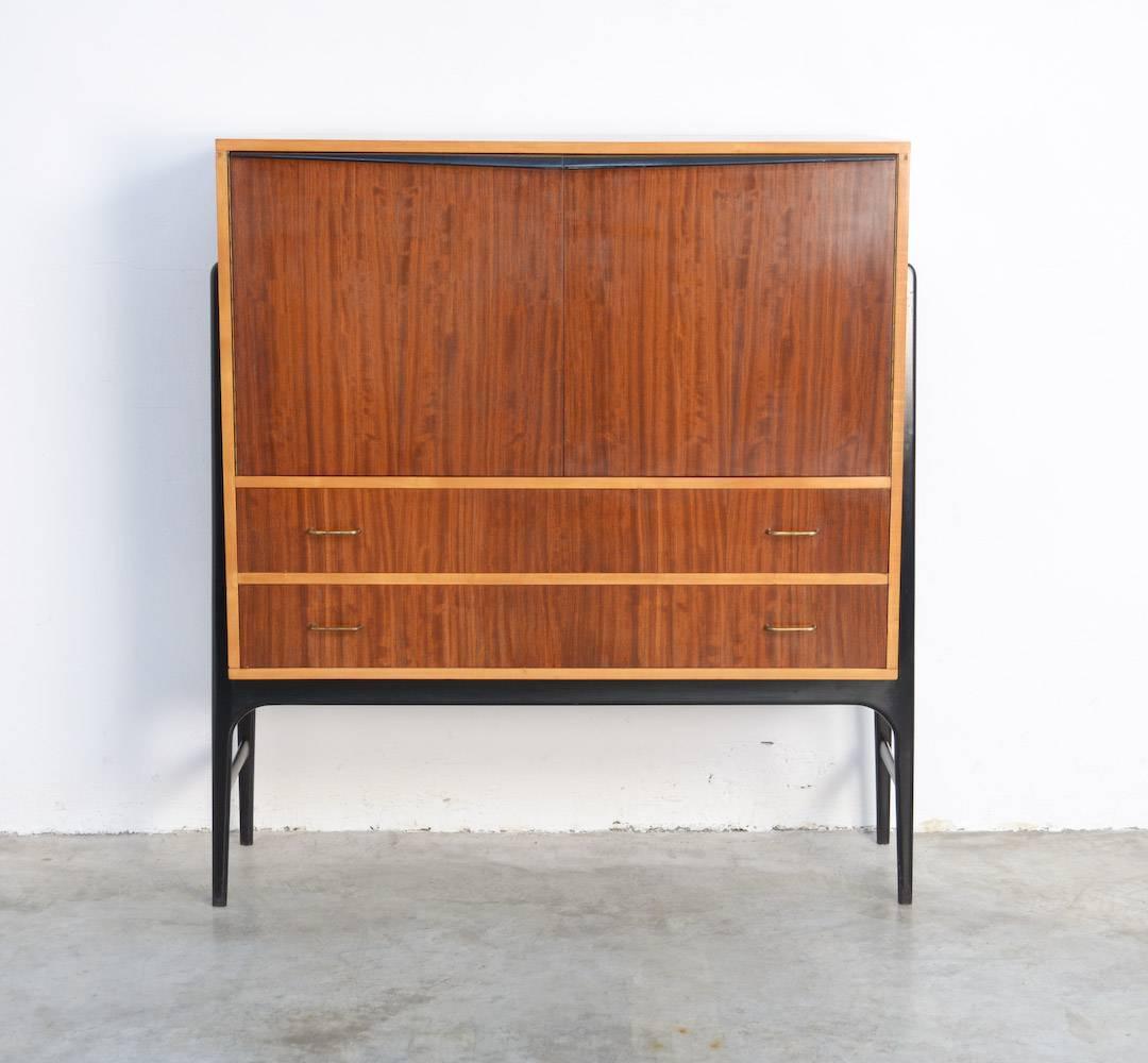 This cabinet is a design of Alfred Hendrickx and can be dated in the late 1950s.
It is measure made in Bubinga wood by Belform. Typical are the elegant black lacquered base and black lacquered handles. The inside is quite unique. You can organise