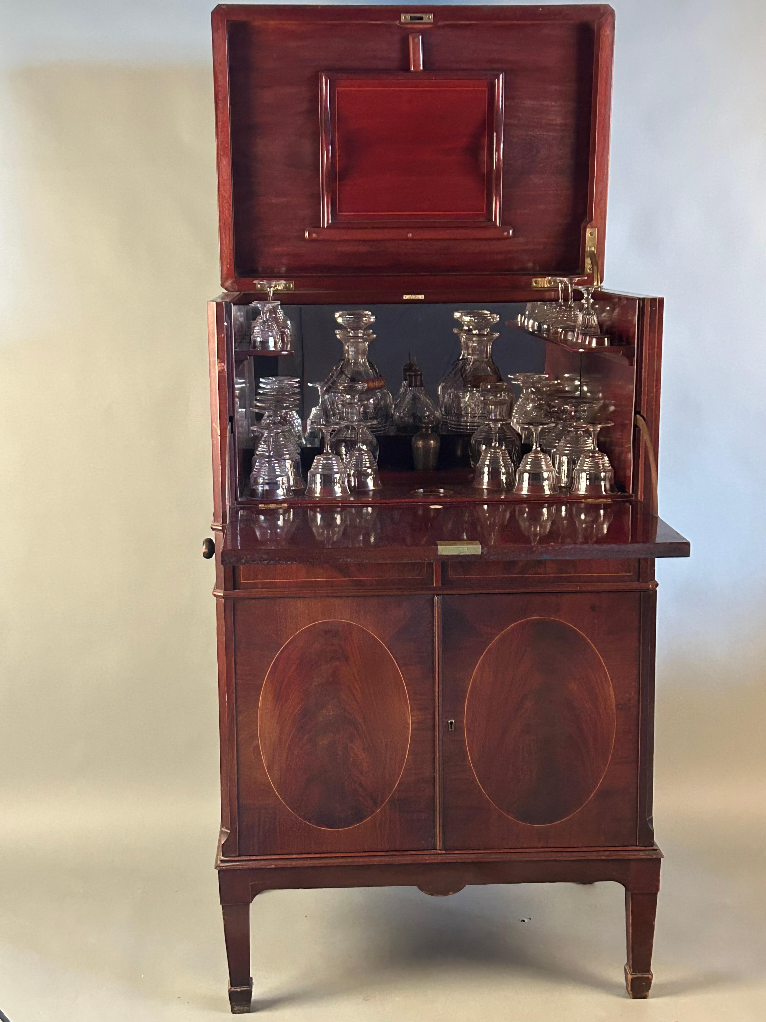 Rear and possibly unique federal style cocktail cabinet. Crotch veneer, mahogany with string inlay, original brass hardware signed by maker. Original removable tray, tapered leg with spade foot. Top lifts, fall front opens to collection of original