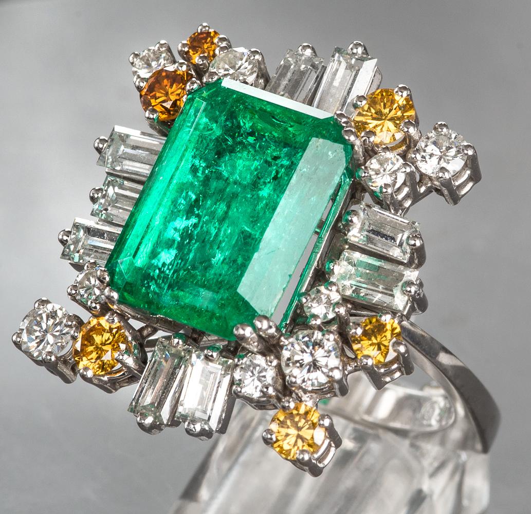 Cocktail ring in 750/18k white gold.
Emerald Columbian circa 8 carat.
24 Diamonds: 
18 white in baguette and brilliant cut.
6 brown in brilliant cut.
Diamonds total circa 2.60 carat.
Designed circa 1970s
Signed 750 KC 2/2901
Length circa 2.5cm,