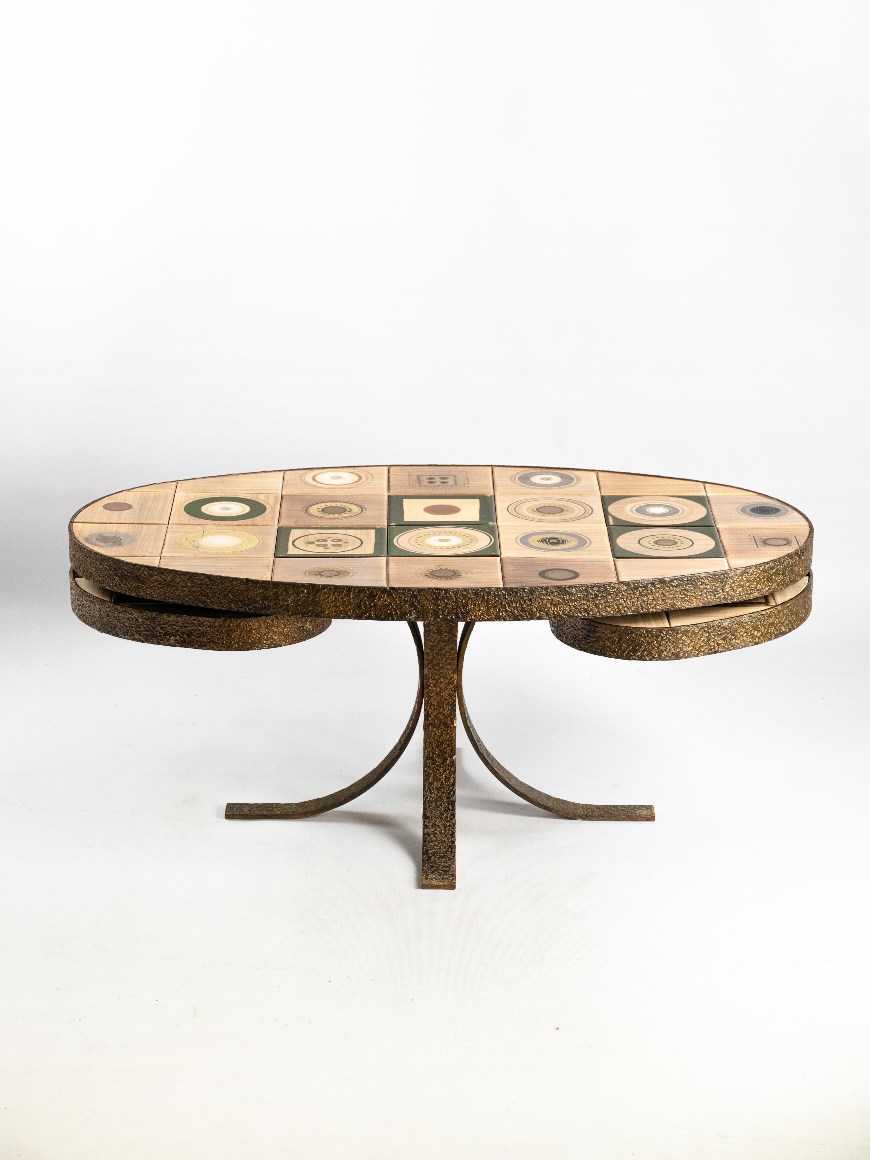 Cette table en céramique, conçue par Georges Pelletier pour La Roue Vallauris dans les années 1970, illustre le charme du design français du milieu du siècle dernier. Le plateau ovale est orné de carreaux peints à la main avec des motifs