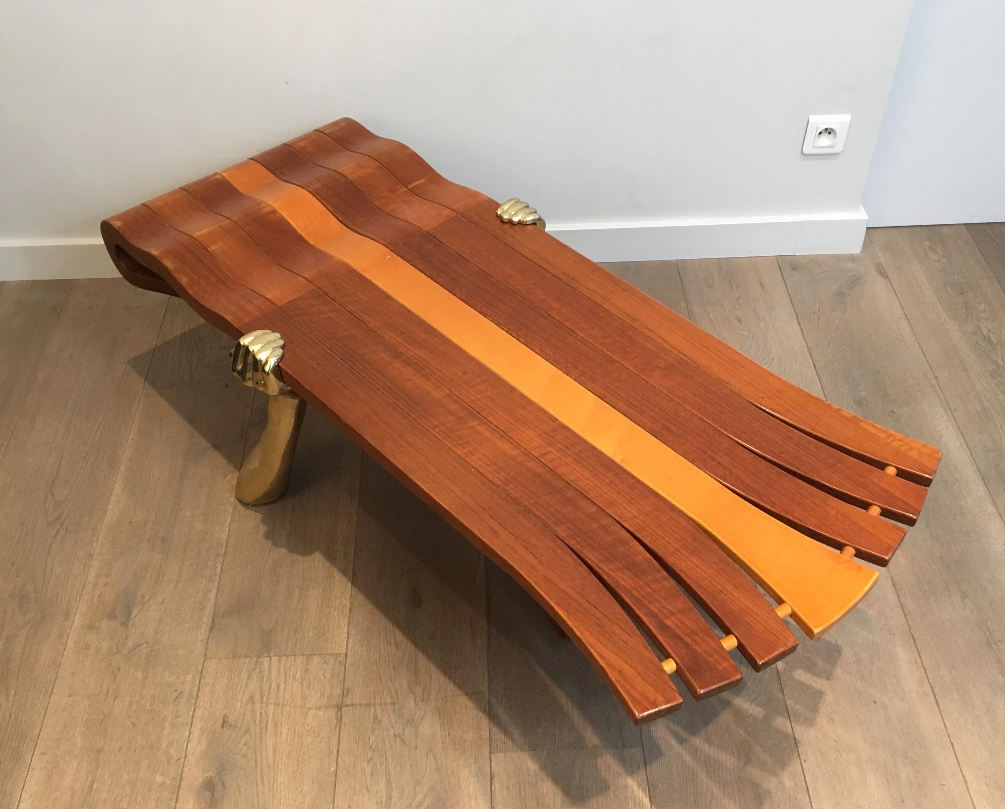 This very nice and unique coffee table is made of a thick freeform wooden top supported by 2 gilt brass arms. This is a very nice quality French work, circa 1970.