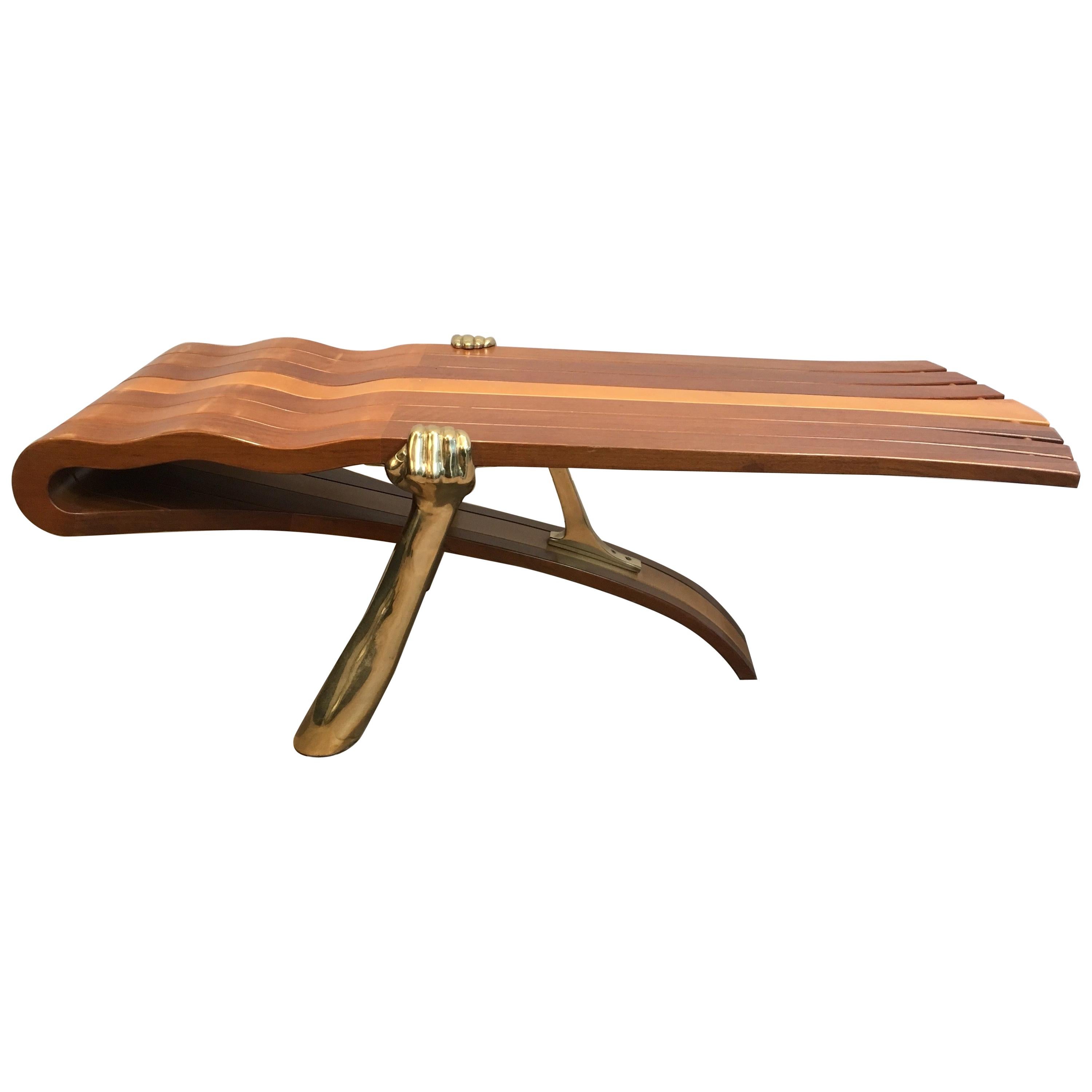 Table basse unique composée d'un plateau en bois épais de forme libre soutenu par des bras en laiton