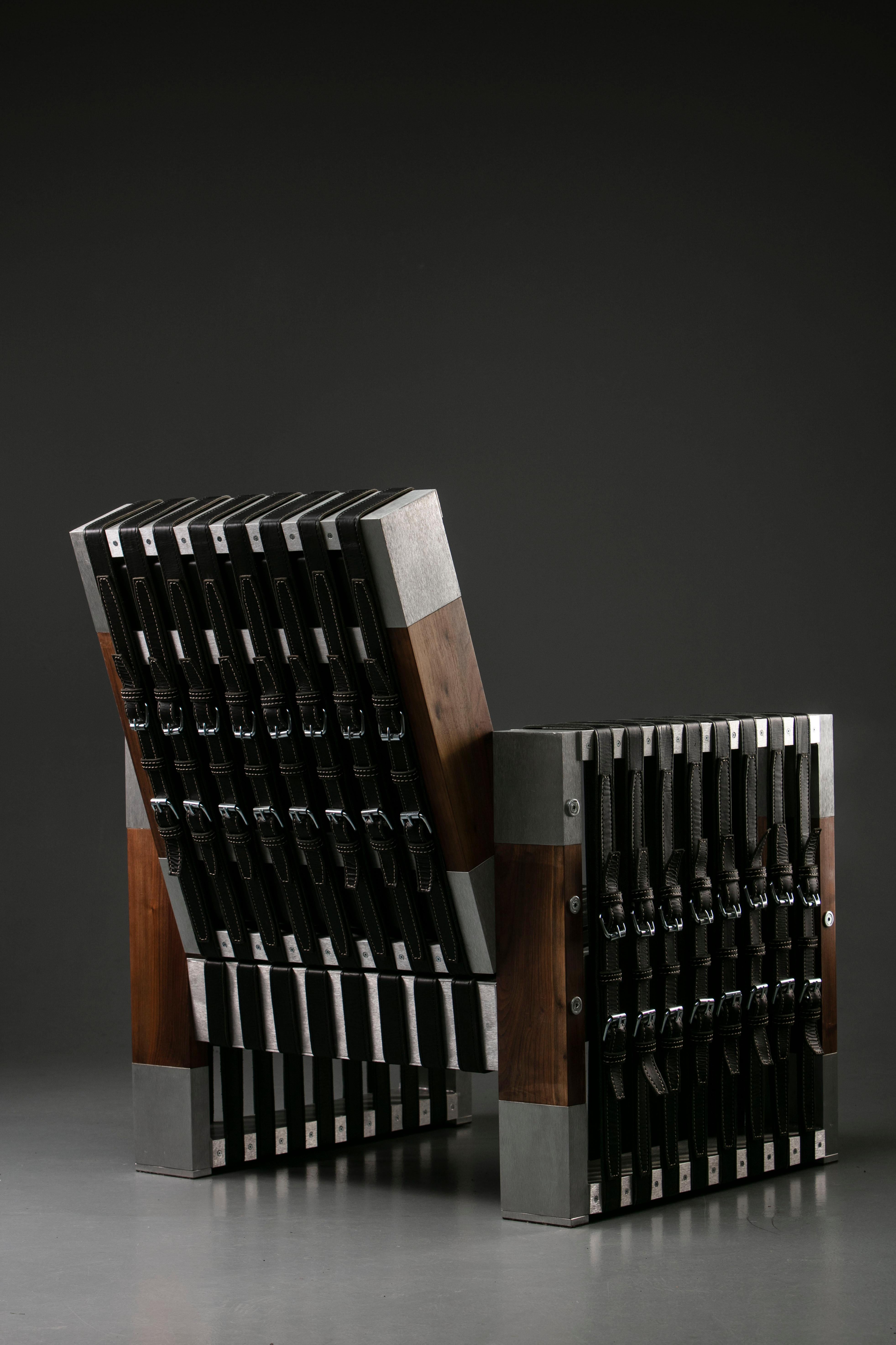 This unique piece is a one-of-a-kind experimental armchair by designer Robert Kovacs. It features a massive, black walnut wood body, with leather straps and polished, brushed aluminium accents. It's a one by one hundred piece, available only on