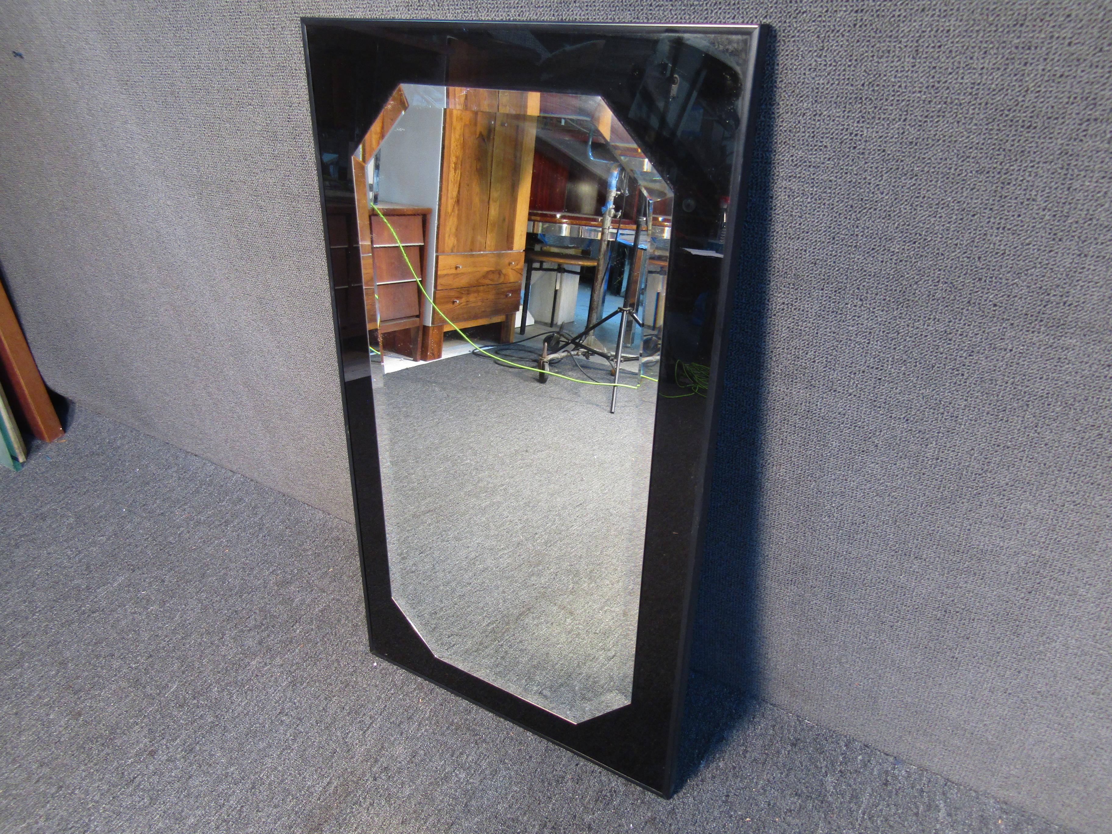 Stylish mirror in the style of Milo Baughman for Thayer Coggin. This mirror features a raised beveled octagonal mirror on a sleek black mirrored back, and is surrounded by a black aluminum framing. A excellent addition to any living or office