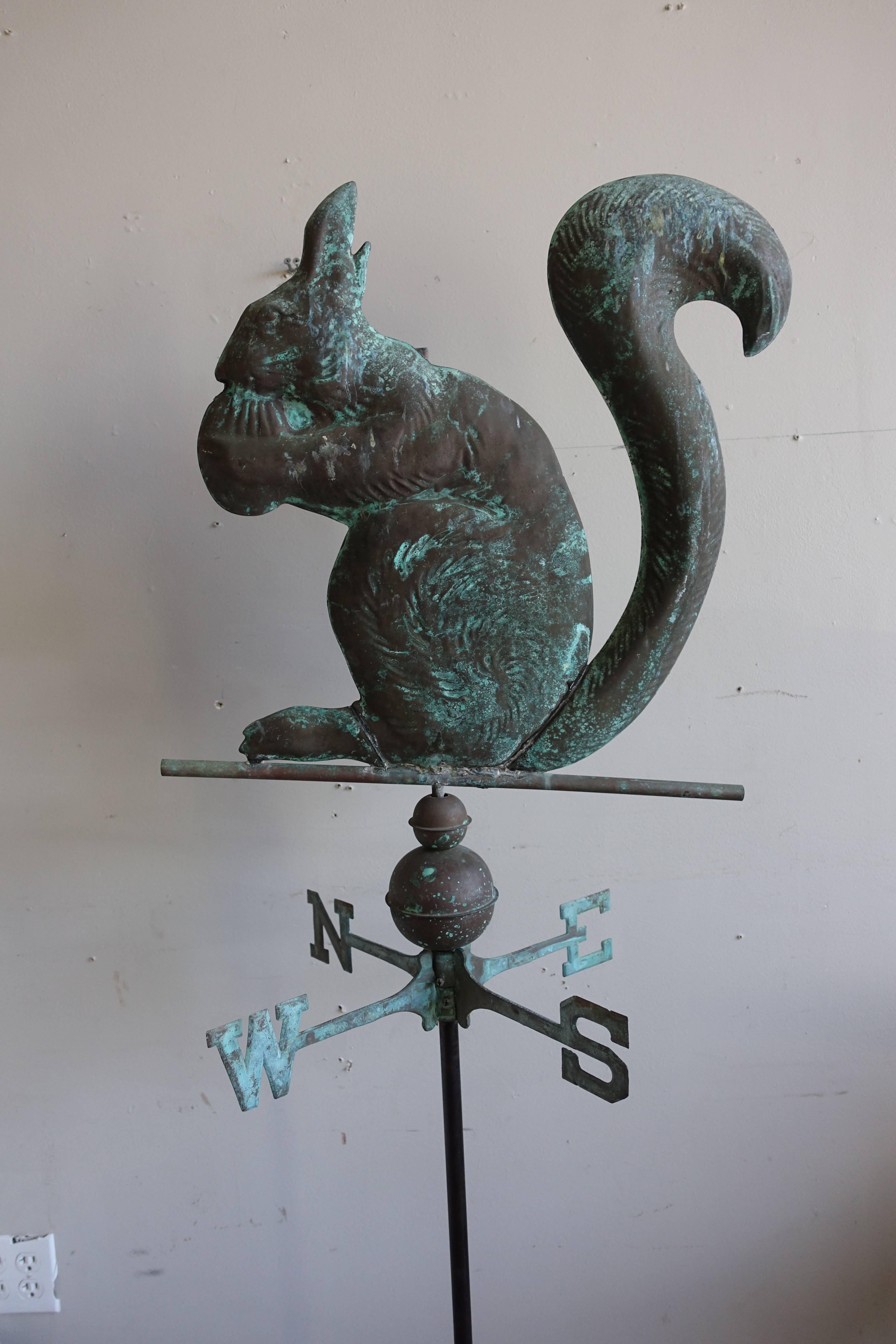 Unique vintage copper weathervane of a squirrel holding a nut. The weathervane has been mounted on an iron base.