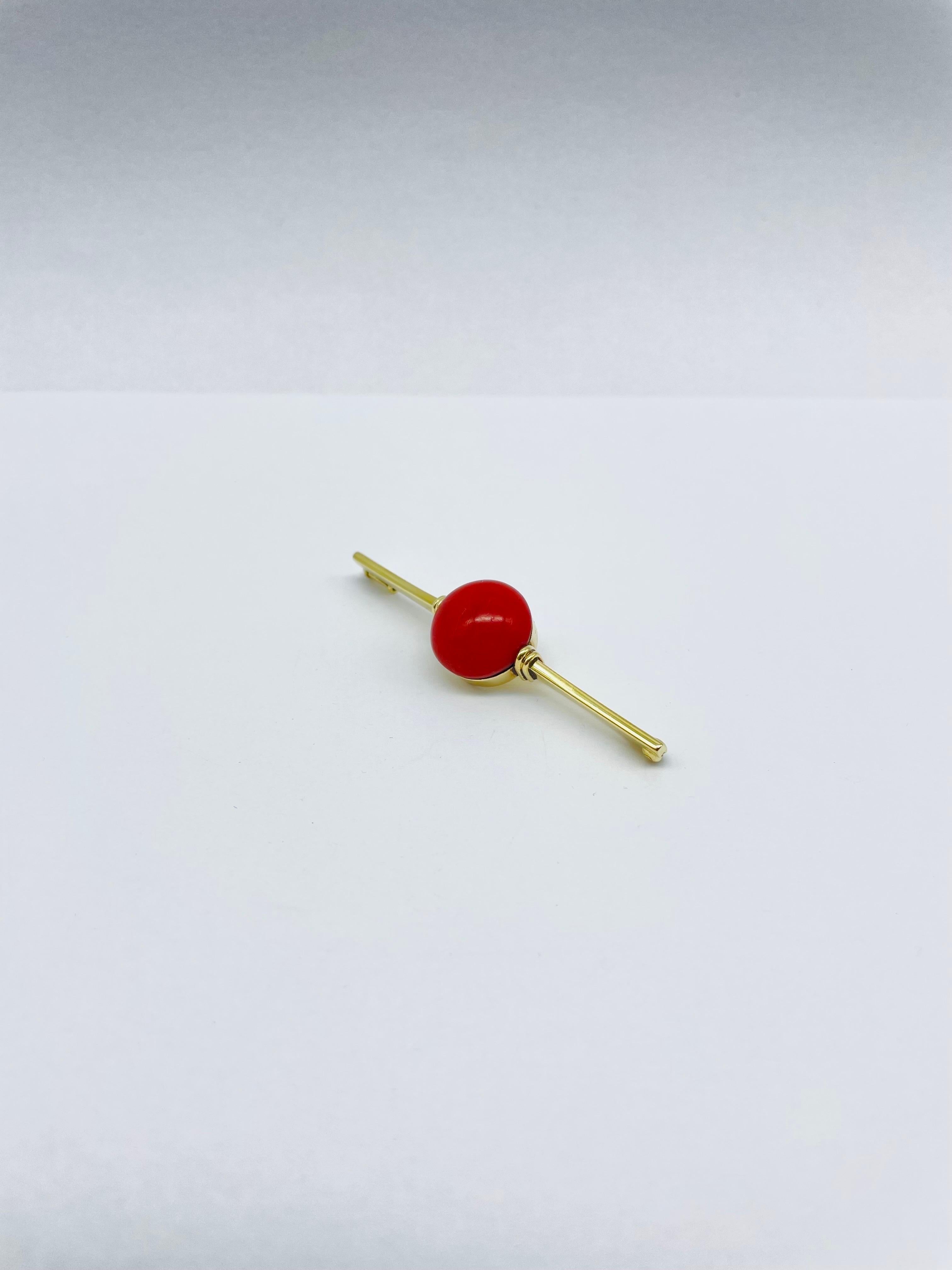 This brooch is a true statement piece, designed to elevate any outfit and capture the attention of those around you.

Crafted from solid 14k yellow gold, this bar brooch features a striking dark red coral at its center. The coral is expertly cut and