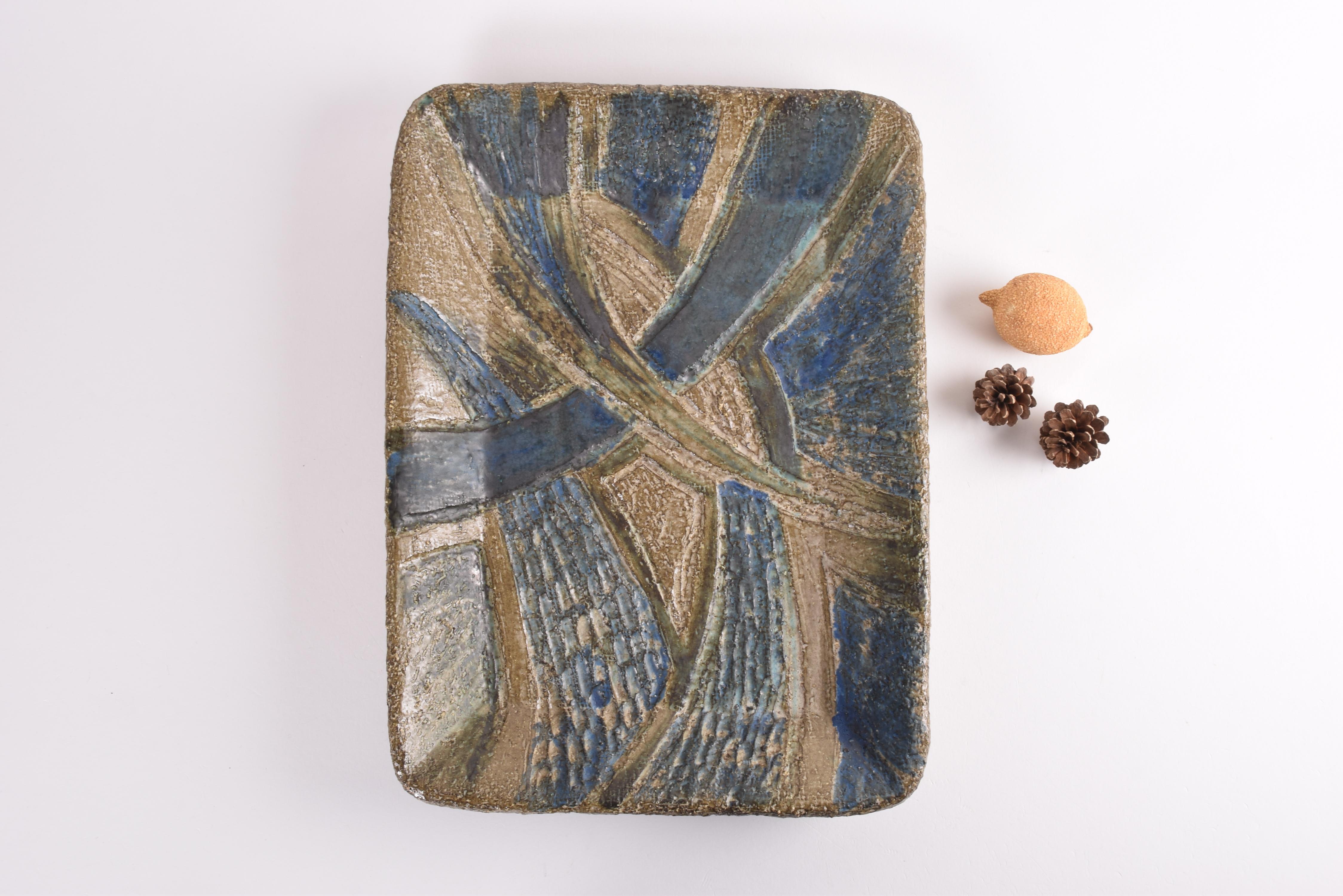Unique large ceramic wall decor in brutalist style. Made ca. 1970s.

The wall platter is made from stoneware and has en abstract and very structured decor with petrol blue, beige, brown and a bit black glaze. It can also be used as a table top