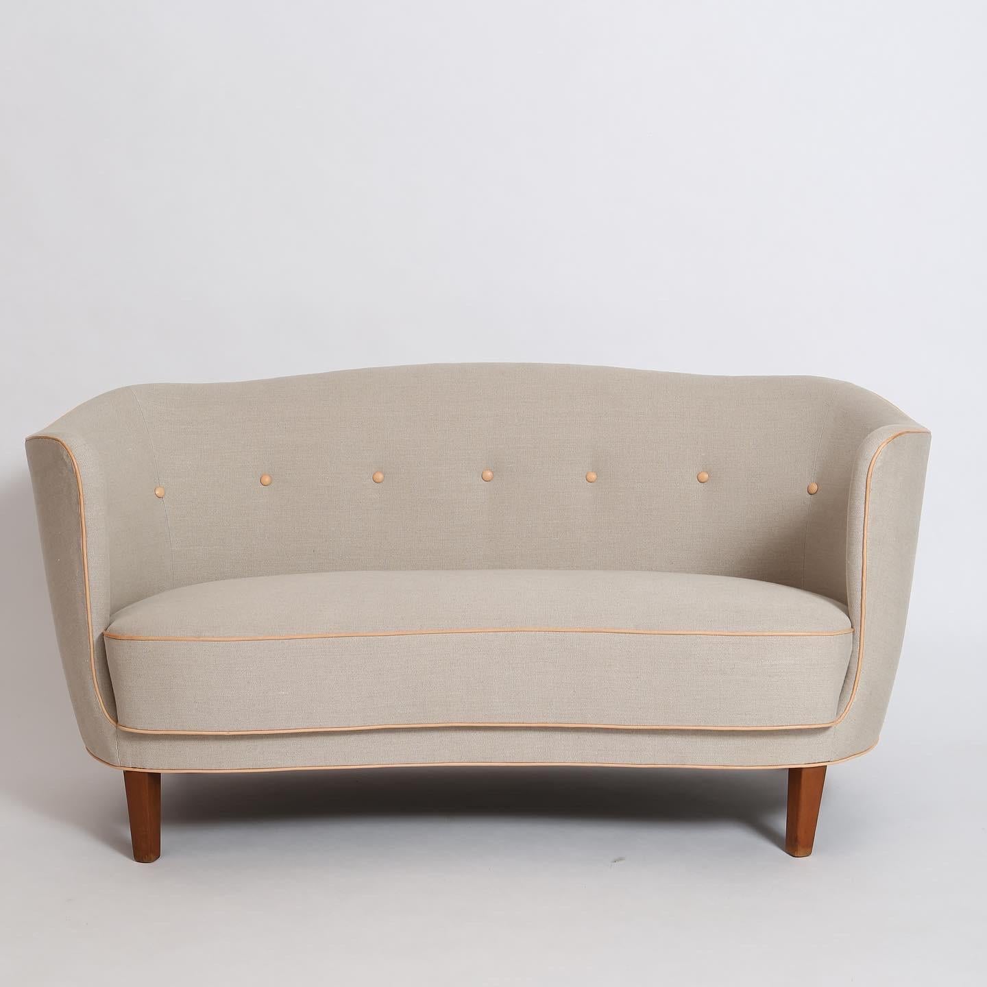 Unique form. Elegantly-curved settee was just redone in linen canvas with vegetable-tanned leather trim and buttons. Legs are solid stained beech. Reminiscent of designs by Nanna Ditzel, Finn Juhl, Tove & Edvard Kindt-Larsen and dates to the early
