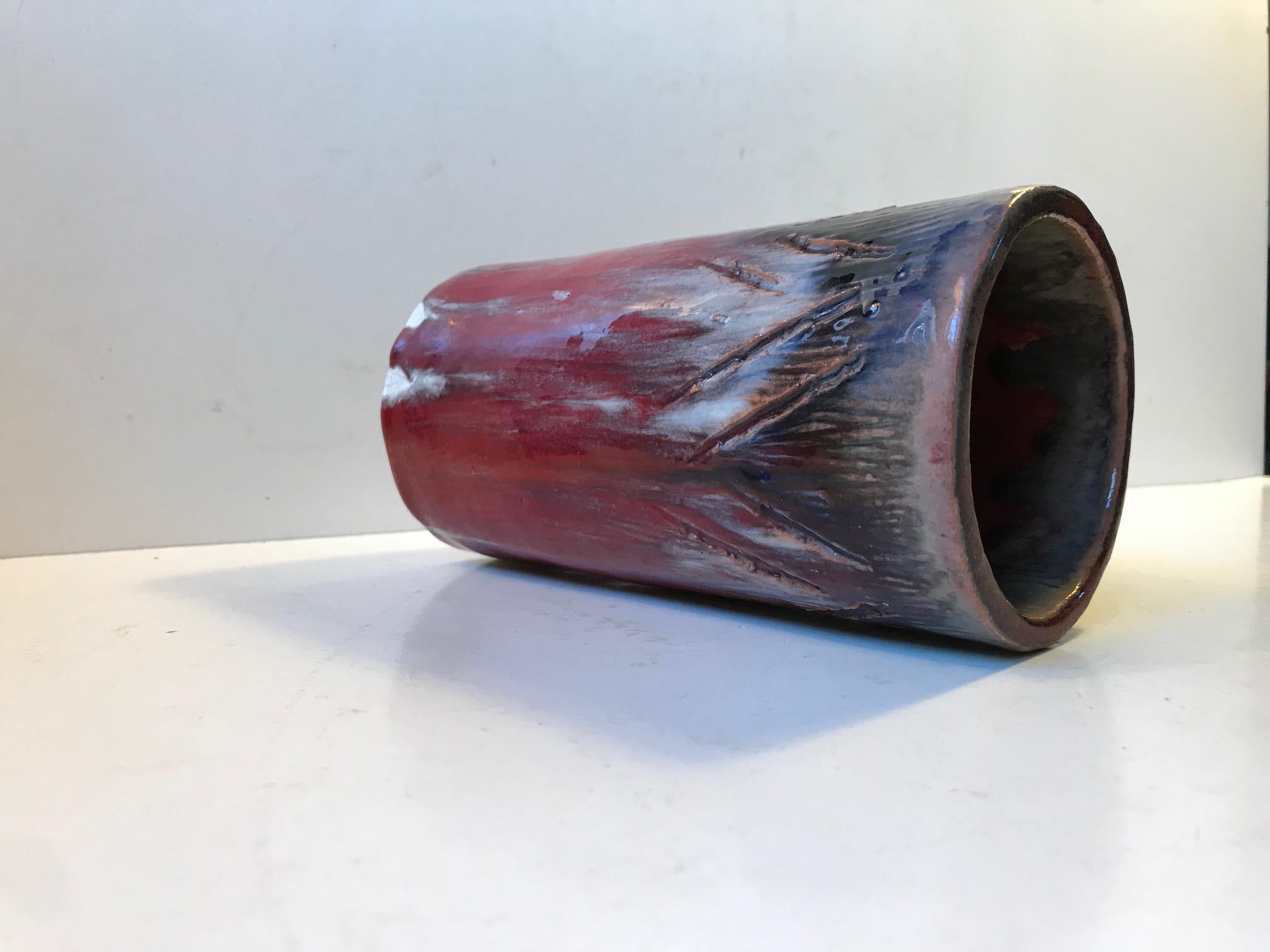 Unique cylindrical ceramic vase with a powerful and dramatic expression created by the use of oxblood-, white drip glaze and highlighted by the use shallow and deep unsymmetrical free-hand incisions.