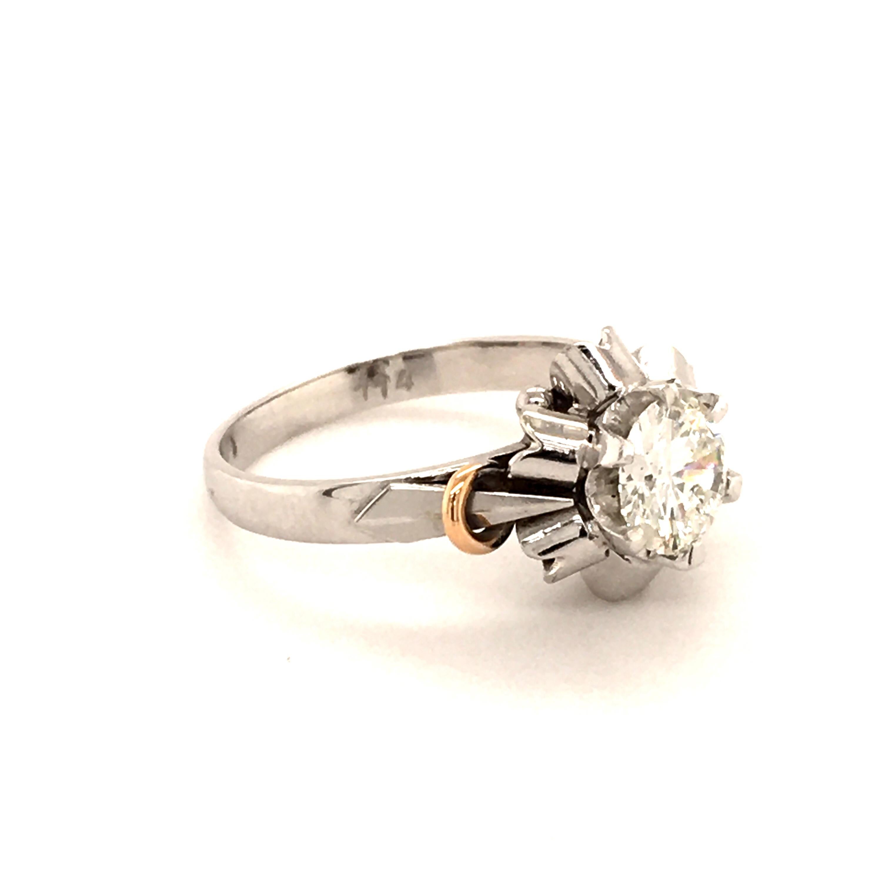 This very pretty and playful ring is set in six prongs with a 1.14 ct, G-I1, round brilliant-cut diamond. Designed with six elements surrounding the center stone resembling a stylized ballerina skirt. The two arcs in red gold on each side of the