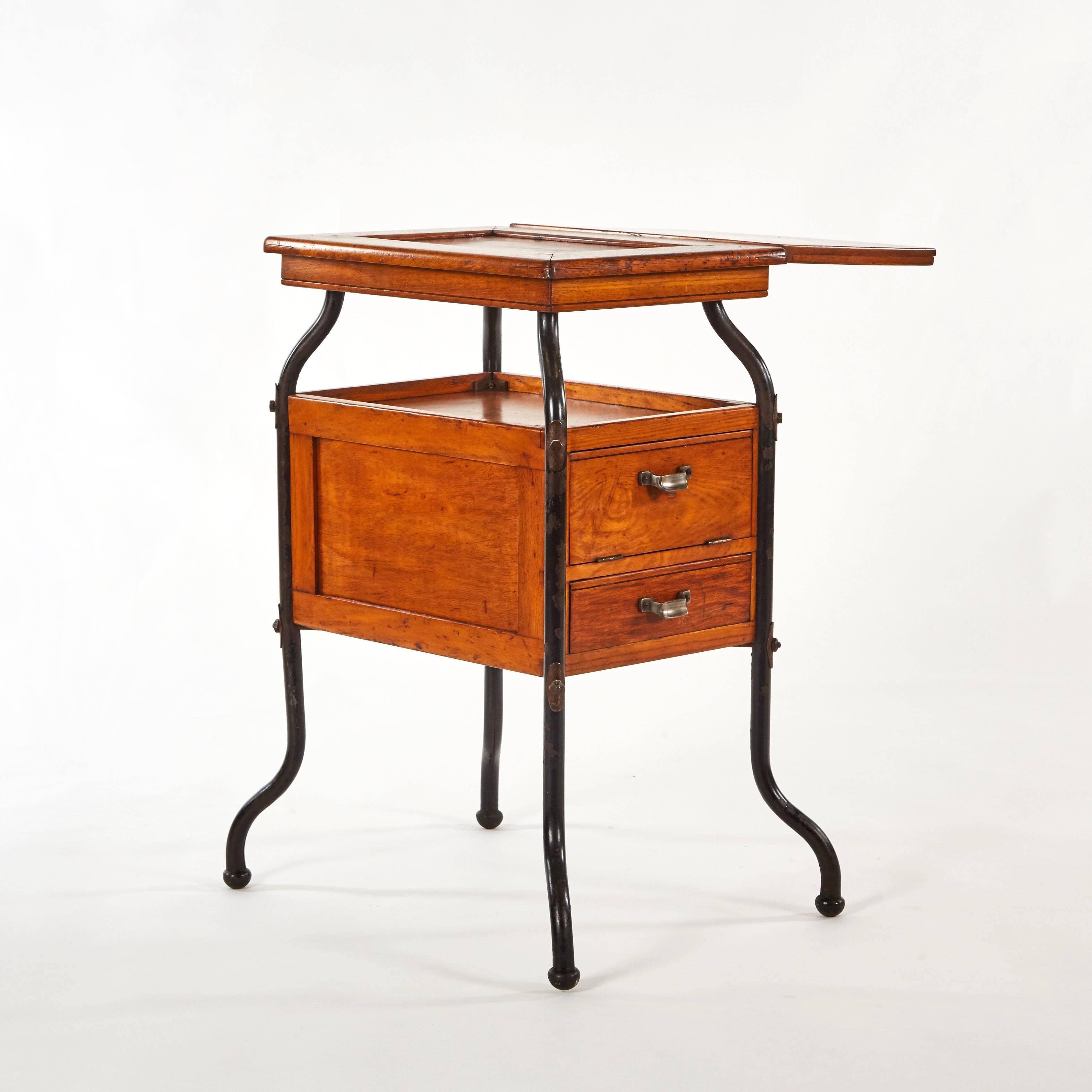 Early 20th-century English adjustable wood and steel side table with two multi-sectioned drawers with cupped handles. With its asymmetric shape and industrial finish, this uniquely multi-functional piece would work well as either a side table or