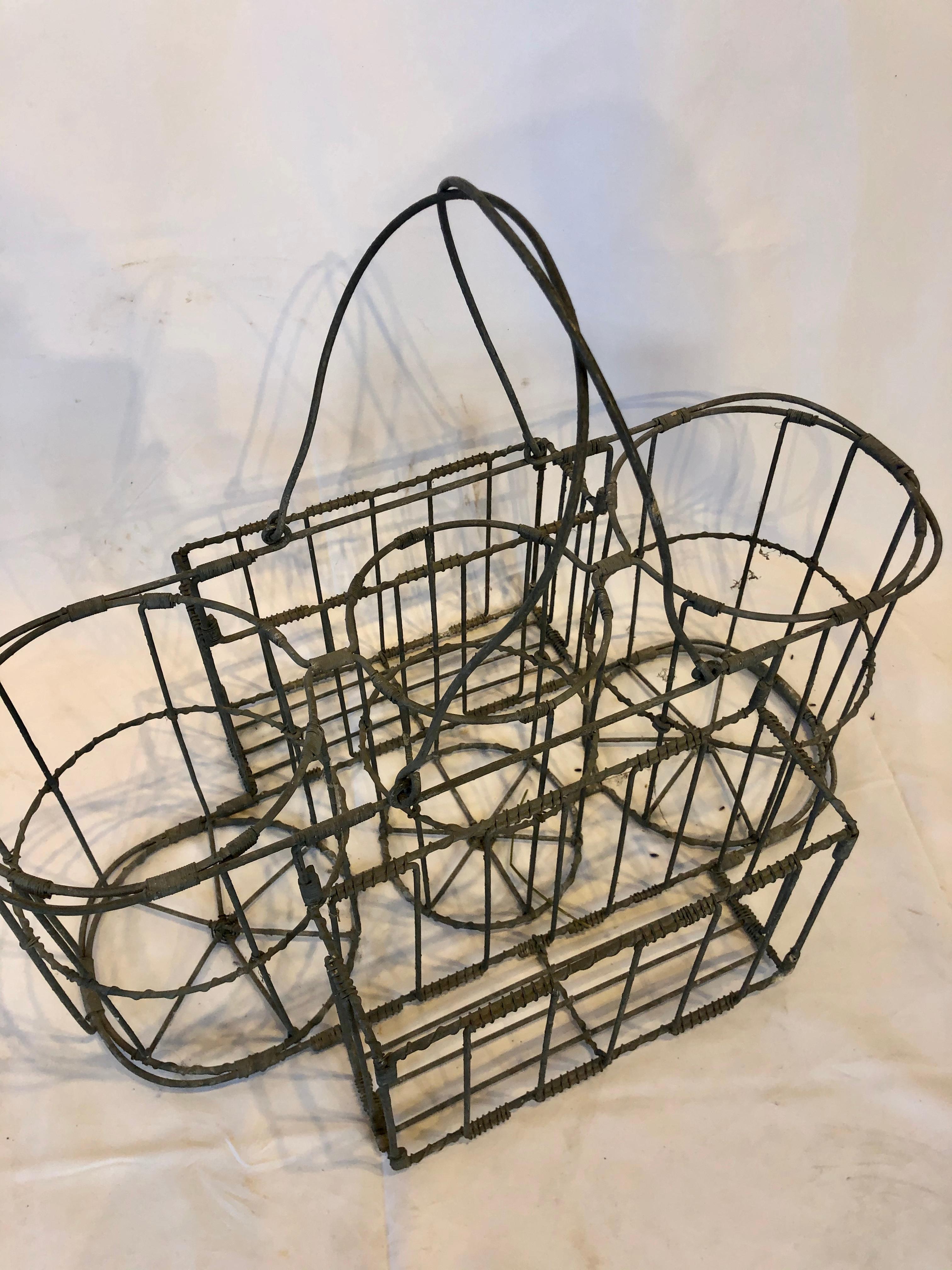 This is a unique early 20th century French bottle carrier basket. Made of metal, the carrier can hold three large bottles and has two side spaces for other items. We believe this carrier was used to transport items for delivery to a home or wine