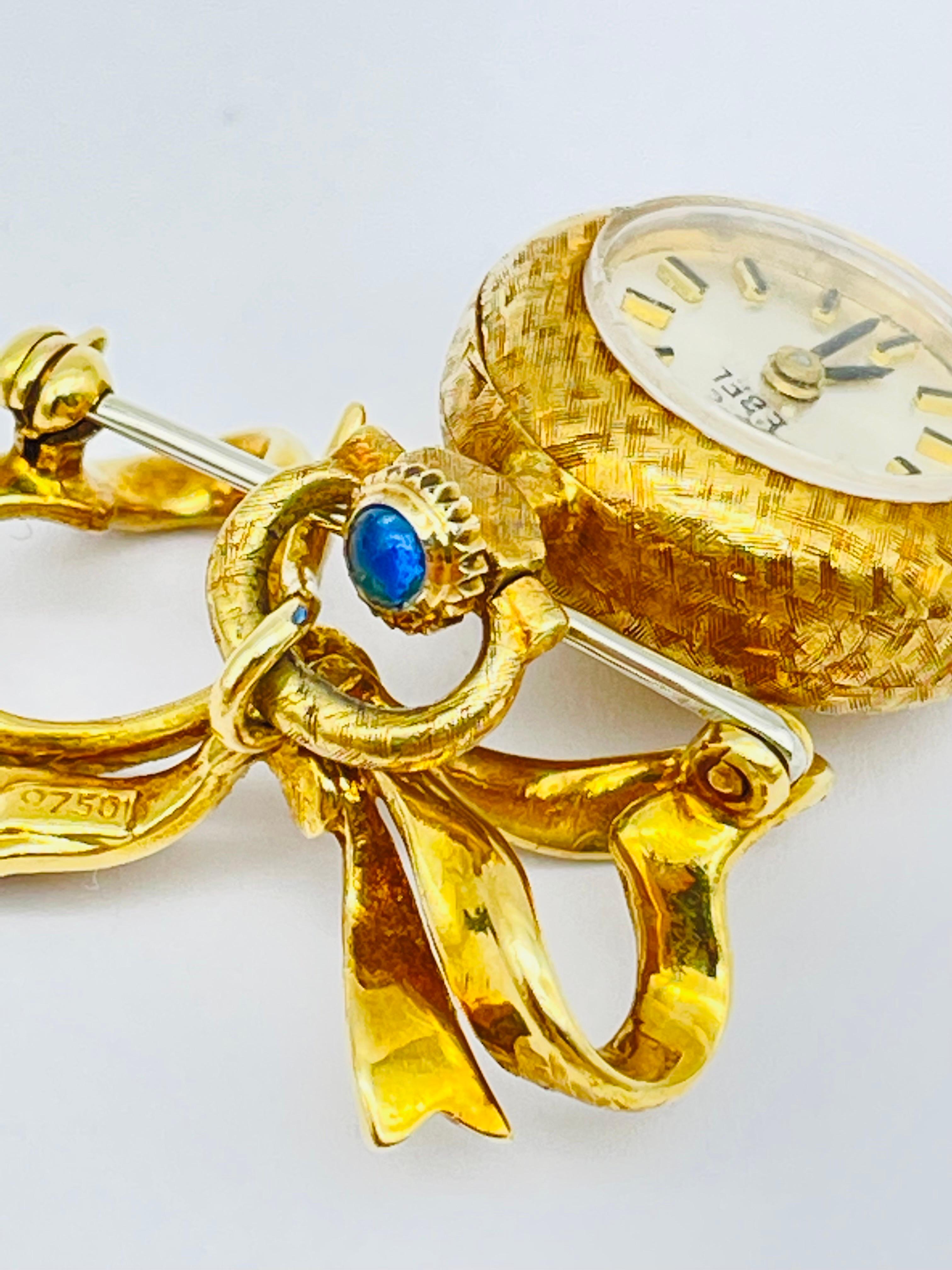 La montre-broche Ebel est une véritable œuvre d'art, réalisée avec un souci inégalé du détail et de la qualité. Le superbe corps en or jaune 18 carats est conçu de manière experte, avec des gravures et des ciselures complexes qui témoignent de la