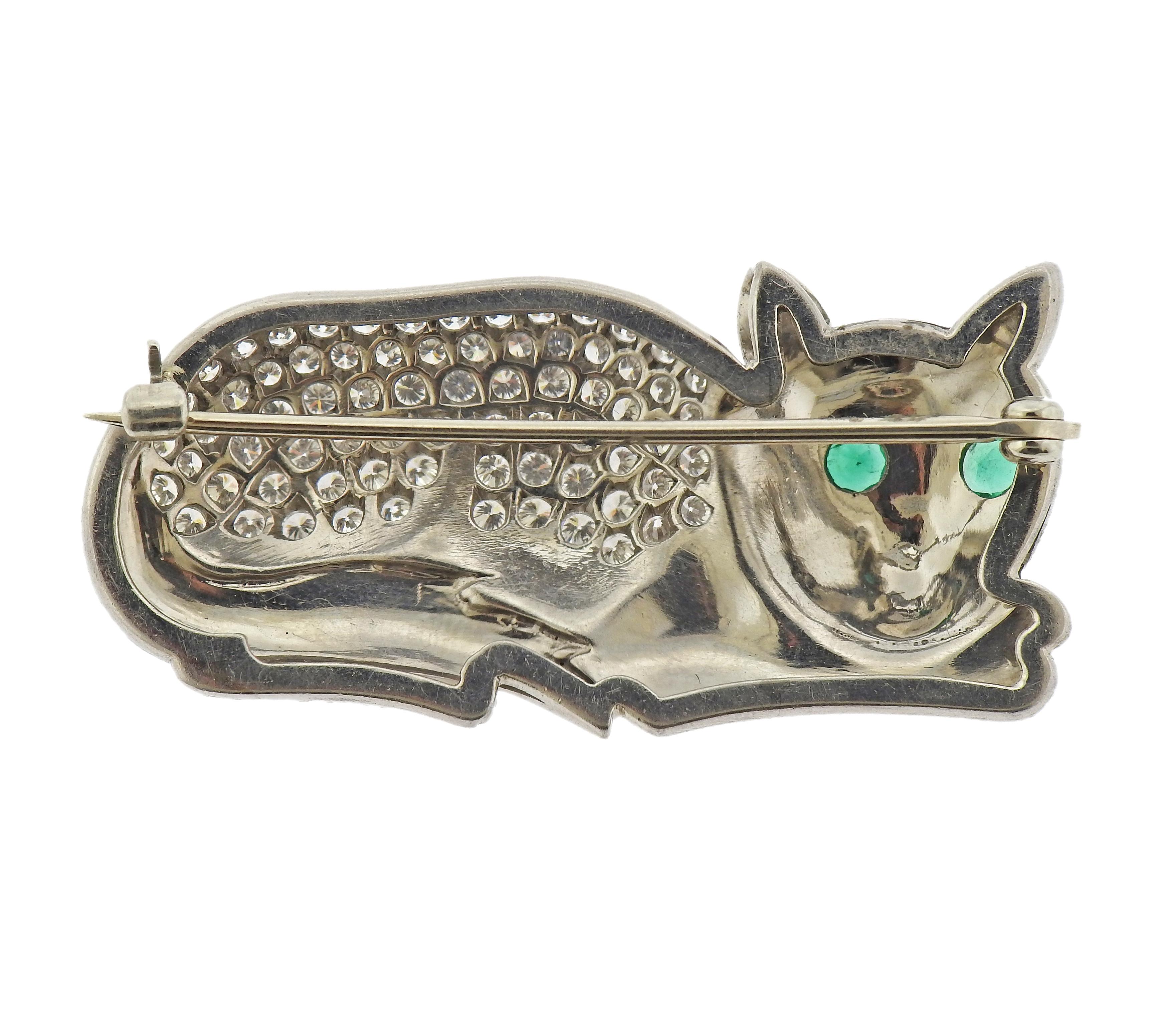 Unique 18k white gold cat brooch, set with two vibrant emerald eyes, and approx. 2.20ctw in diamonds. Brooch measures 2