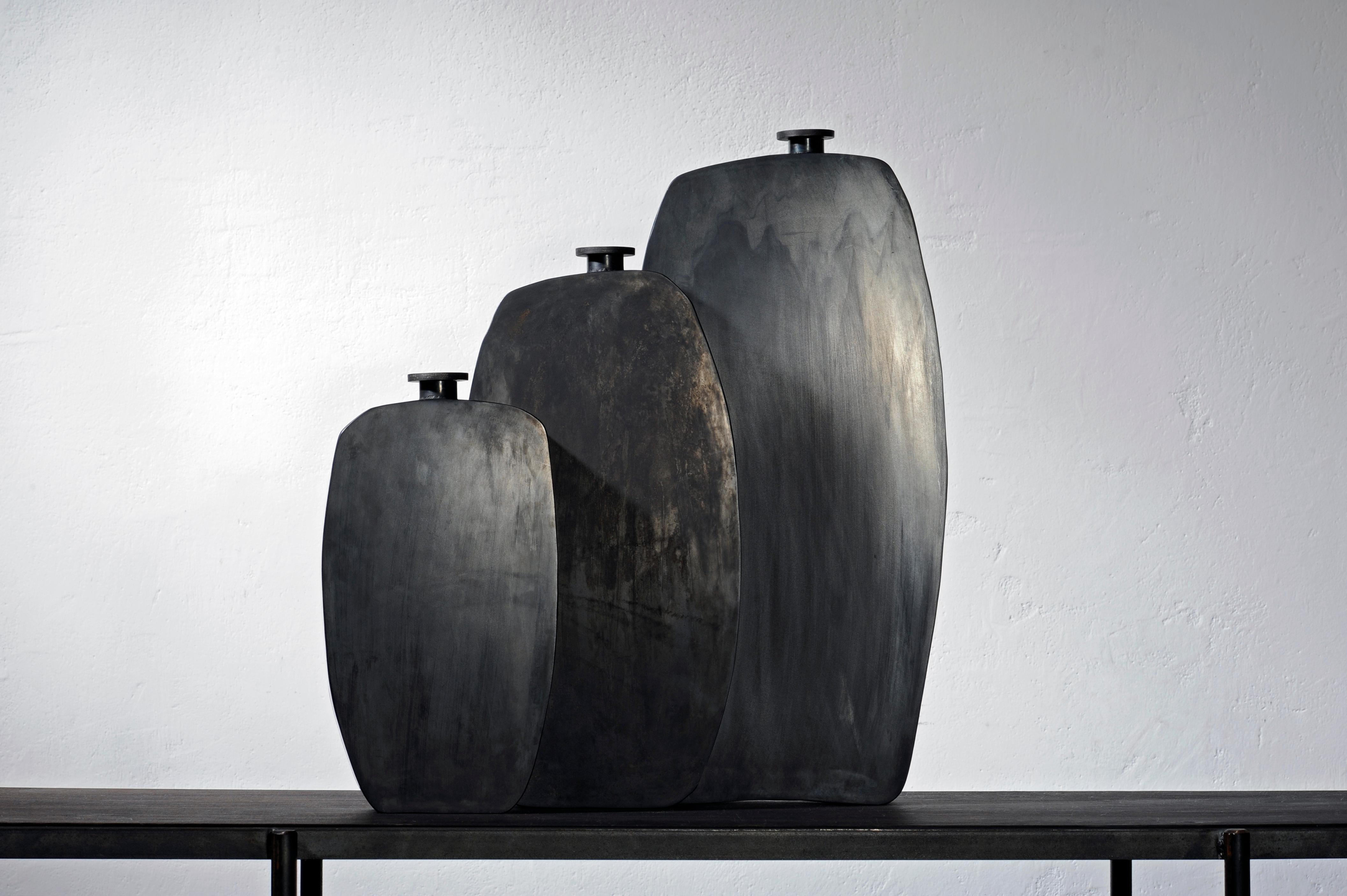 Set of three steel bottles
Signed and numbered vases

Measures: Small steel bottle
15 x 5 x H 28.5 cm
Medium steel bottle
19 x 5 x H 37 cm
Large steel bottle
22 x 5 x H 46 cm
Finish black patina on steel, wax.
  