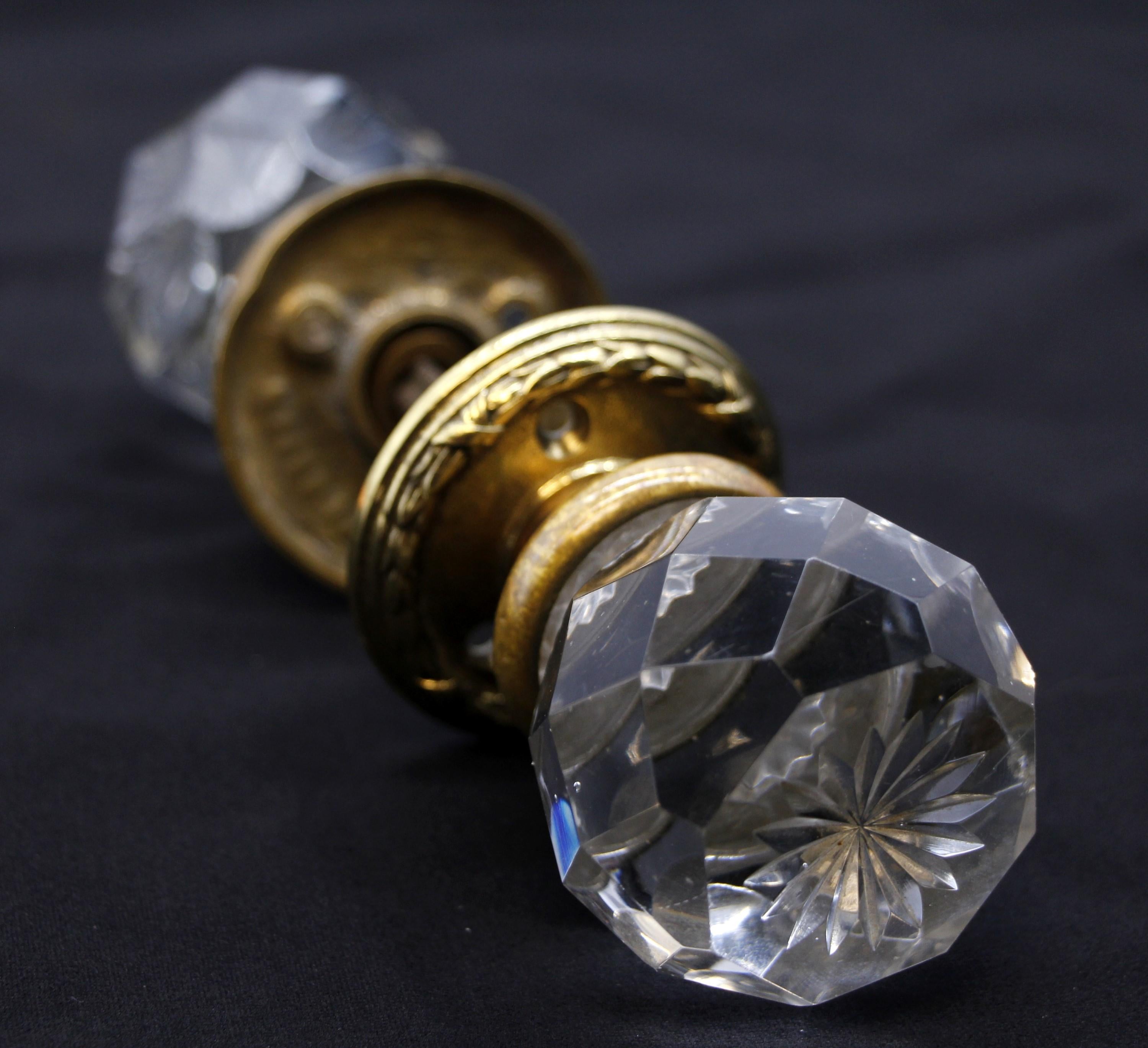 Rare early 20th century clear glass antique faceted door knob set with a center etched floral design. Set included two ornate brass rosettes, two doorknobs and one spindle. Both rosettes are marked Clodian P 29524. Some small scrapes and chips.