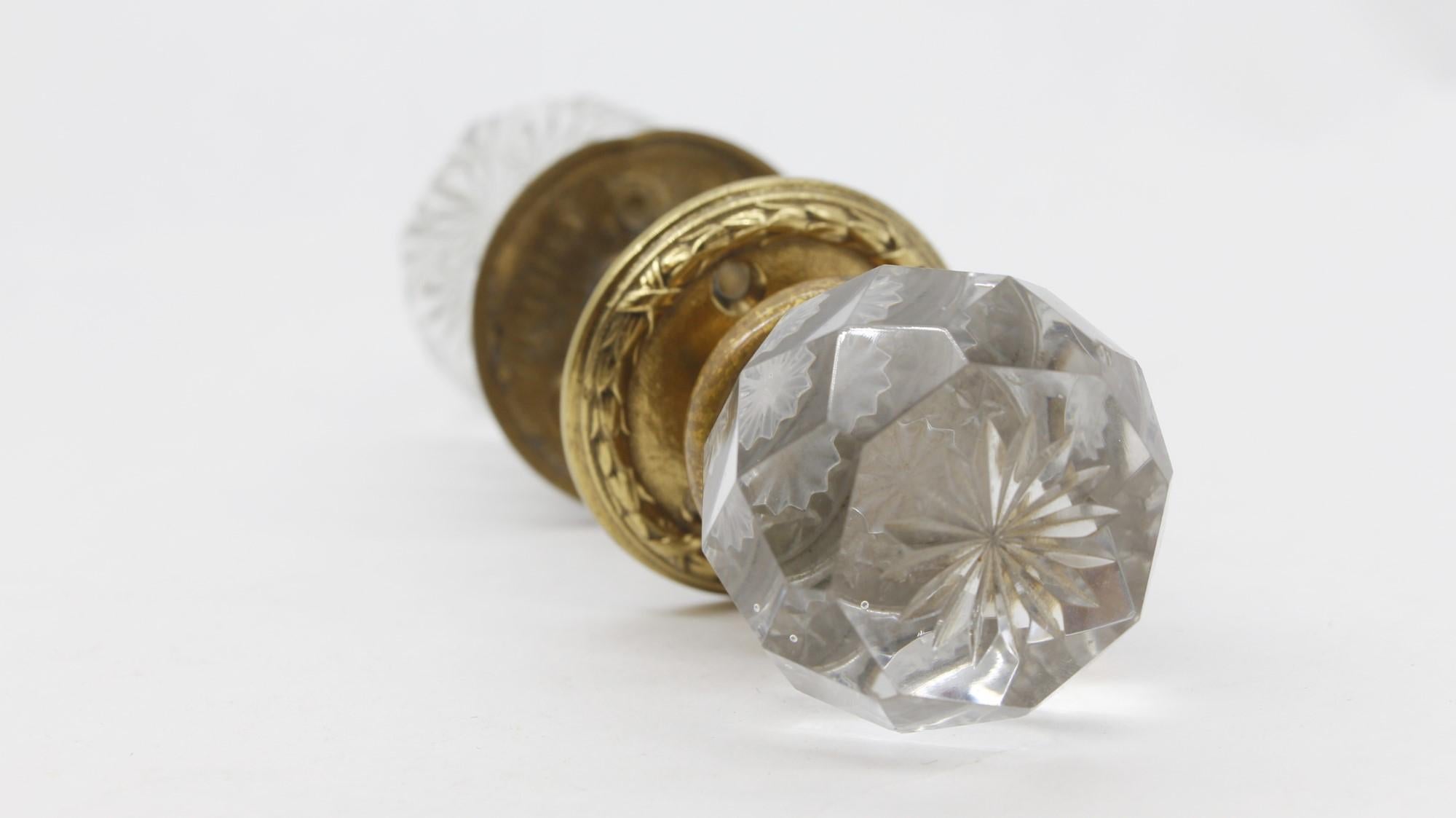 Rare early 20th century clear glass antique faceted door knob set with a center etched floral design. Set included two ornate brass rosettes, two doorknobs and one spindle. Both rosettes are marked Clodian P 29524. Some small scrapes and chips.