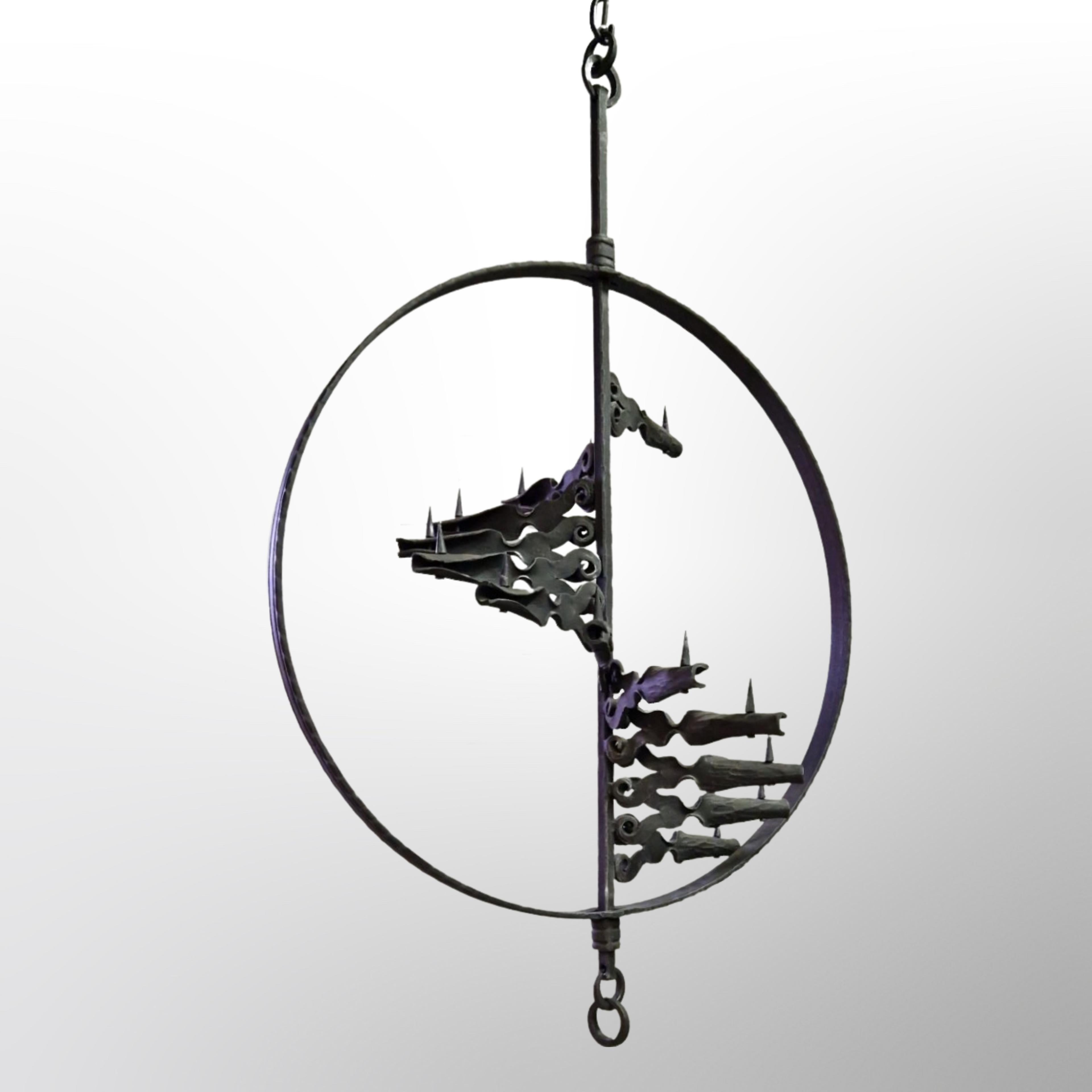 Large hanging candle holder in the arts and crafts style. It is made from solid cast iron. It has 13 arms set inside a ring and fixed to a central axis. The arms spiral down on the axis. Each arm holds one candle. The purple globe candles are