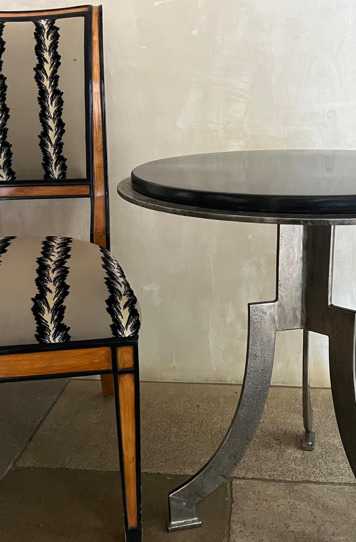 Handgefertigter Beistelltisch aus geschliffenem Stahl mit einer dicken Platte aus schwarzem Kunstmarmor, umgeben von einem Art-Déco-Muster aus gestanztem Stahl. Die Stahlbeine sind auf rechteckigen Pads gelagert.

