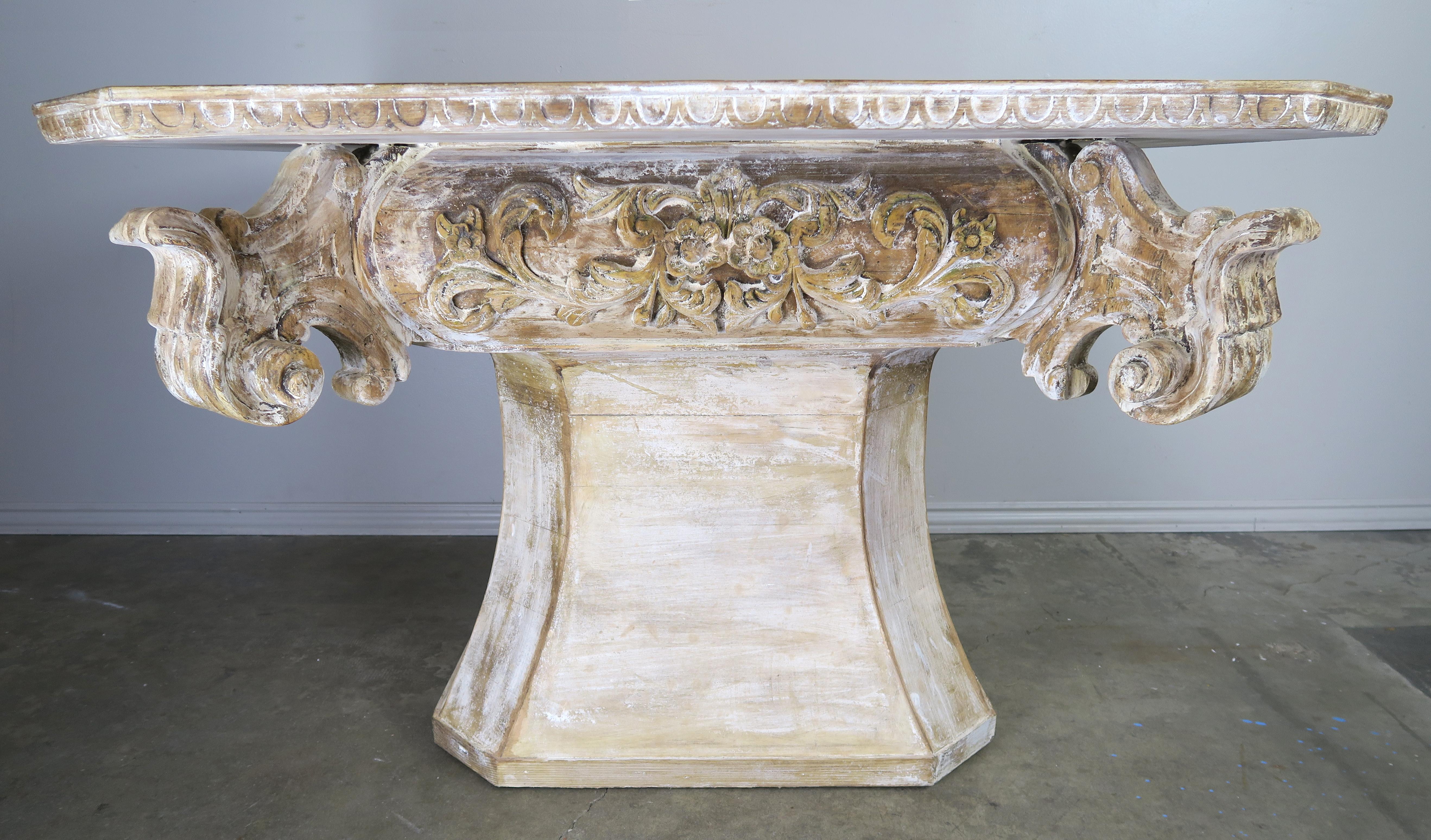 Unique painted dining or center table with a beautiful white washed finish, 1930s. The table has a slight rectangular shaped top with straight corners and an egg and dart carved detail along the edge. The top is supported by an eight sided