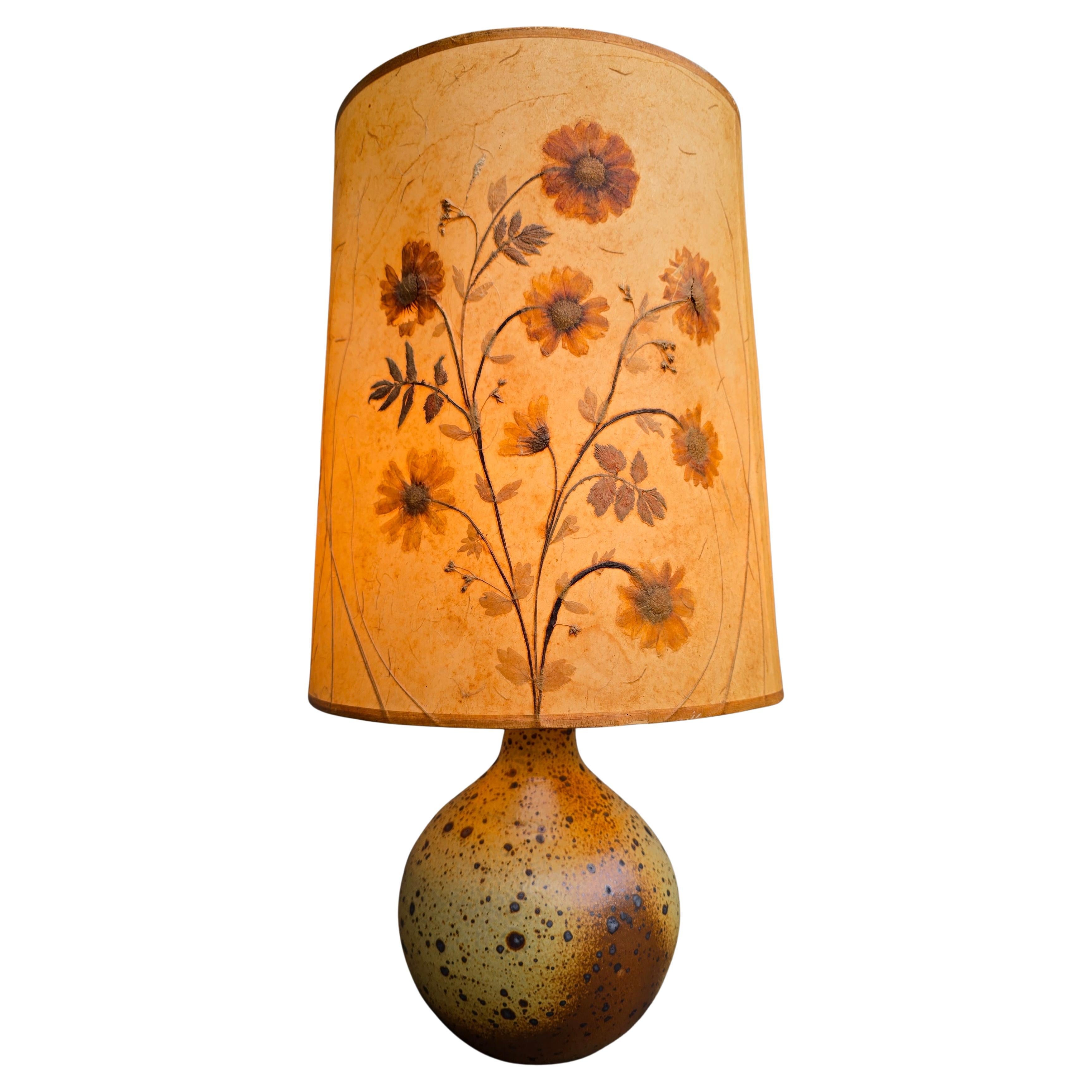 Lampe de table unique en céramique française - années 1950

Cette pièce vintage authentique allie l'élégance à la beauté naturelle grâce à l'abat-jour magnifiquement fait à la main, qui est décoré de véritables fleurs et feuilles séchées. Les