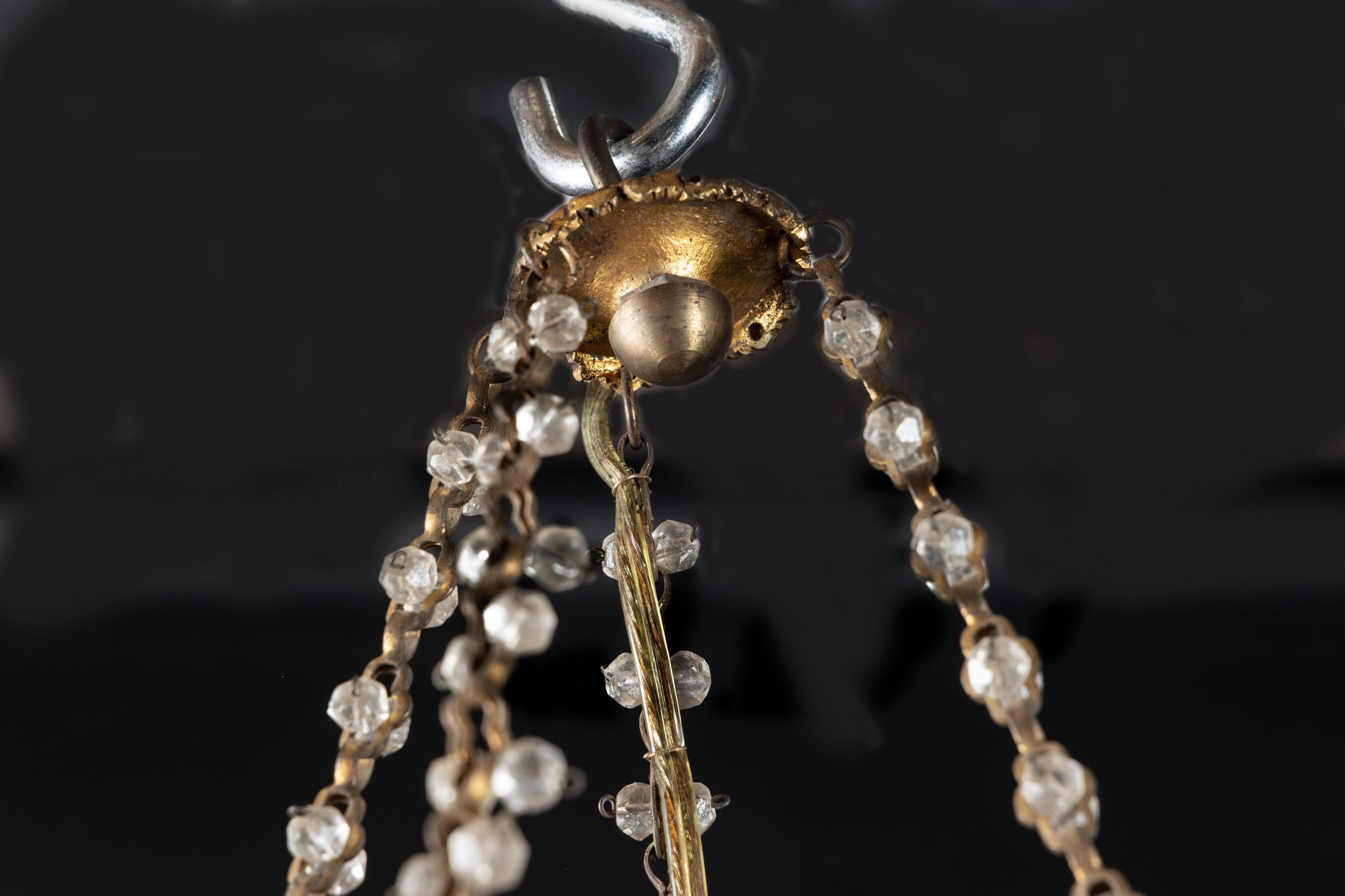 Lustre en bronze et cristal de style Louis XVI du début du 20e siècle, original et fantaisiste. Le lustre comporte 4 lumières dirigées vers le bas pour montrer la nouveauté de la lumière électrique utilisée à l'époque de sa création. La pièce est