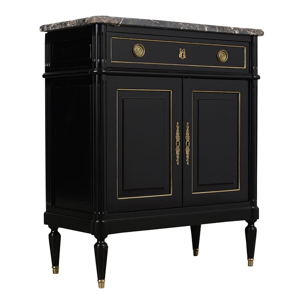 This 1950s Louis XVI-style mahogany server has a dark grey marble top with beveled edges and elegant ebonized finish. The single top drawer and two doors are adorned with a simple brass molding and brass keyholes. Inside there's one adjustable