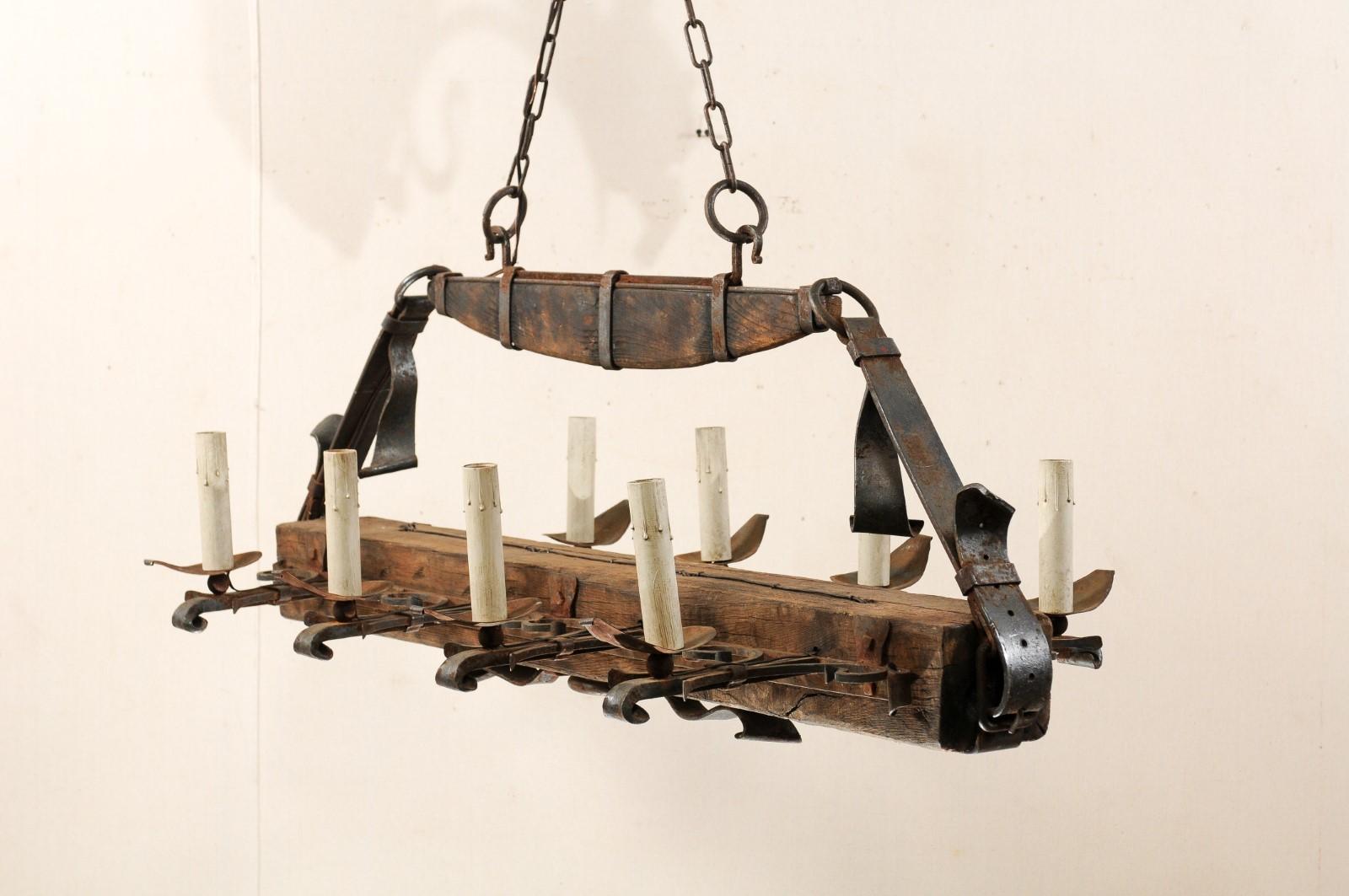 A French wooden beam and iron eight-light chandelier from the mid-20th century. This unusual vintage hanging light fixture from France features a rectangular-shaped, horizontally positioned wood beam which is wrapped and suspended to the upper