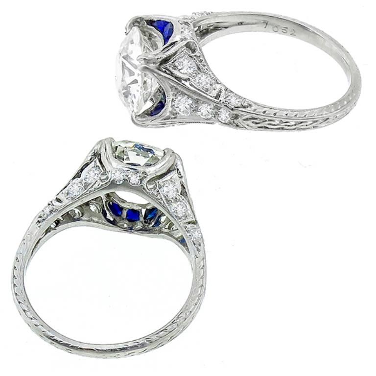 This amazing engagement ring from the Art Deco era, is centered with a sparkling GIA certified old European cut diamond that weighs 2.12ct. graded J with VS1 clarity. The center diamond is accentuated by faceted cut sapphire and old mine cut diamond