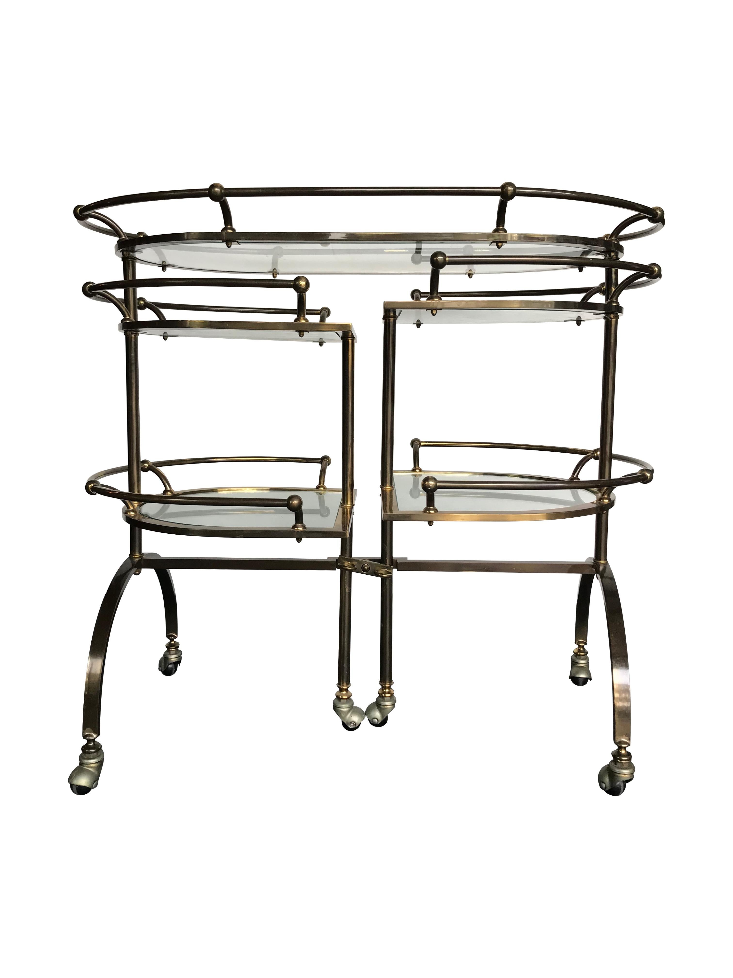 A unique gilt metal bar trolley with swing out demilune shelves, each with two glass shelves, with central lock to hold them in place. On gilt metal legs with original castors.
