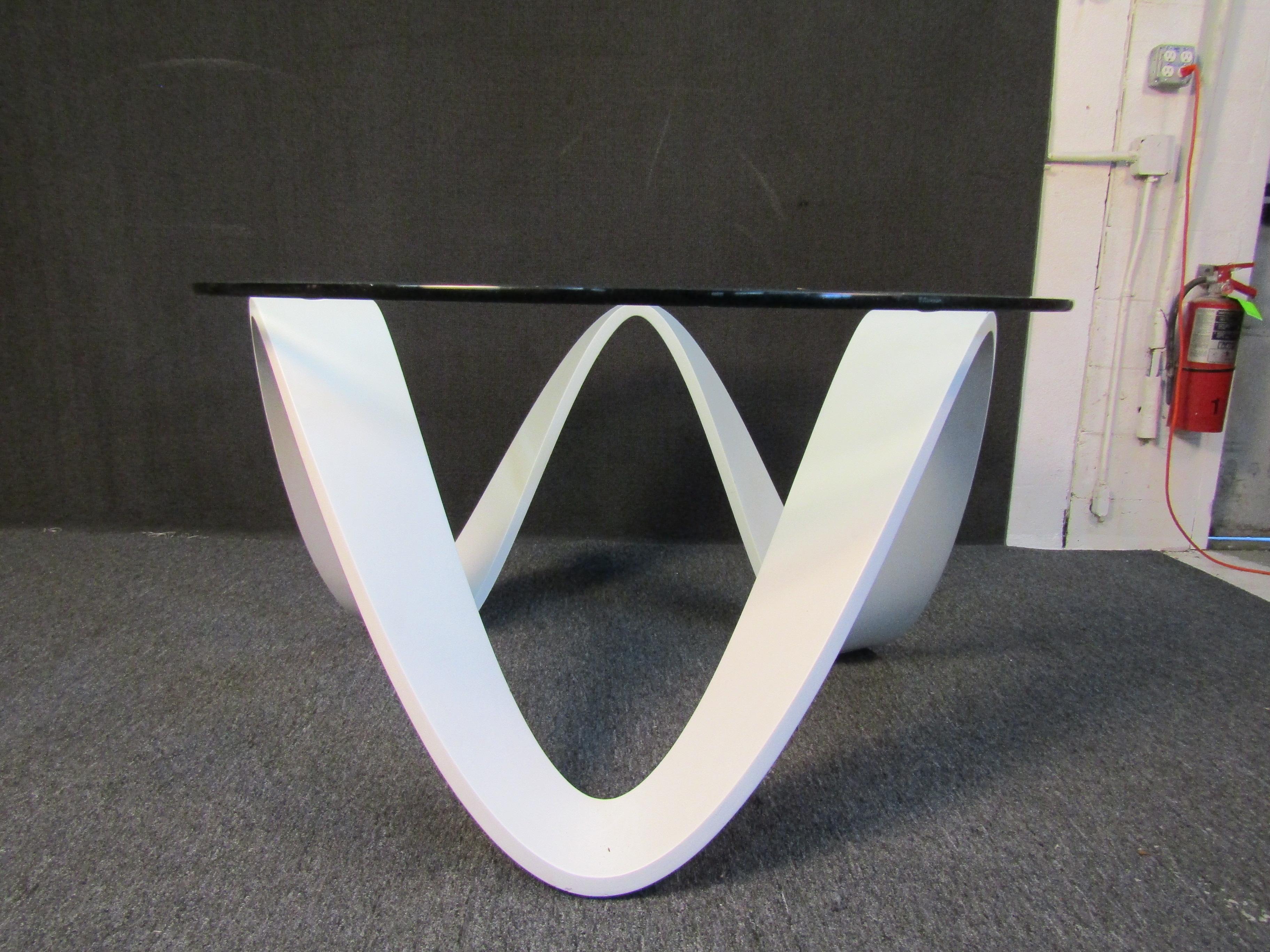 Unique glass table featuring a flowing white base on three contact points. The top is round and has an elegant beveled glass. Please confirm location NY or NJ.