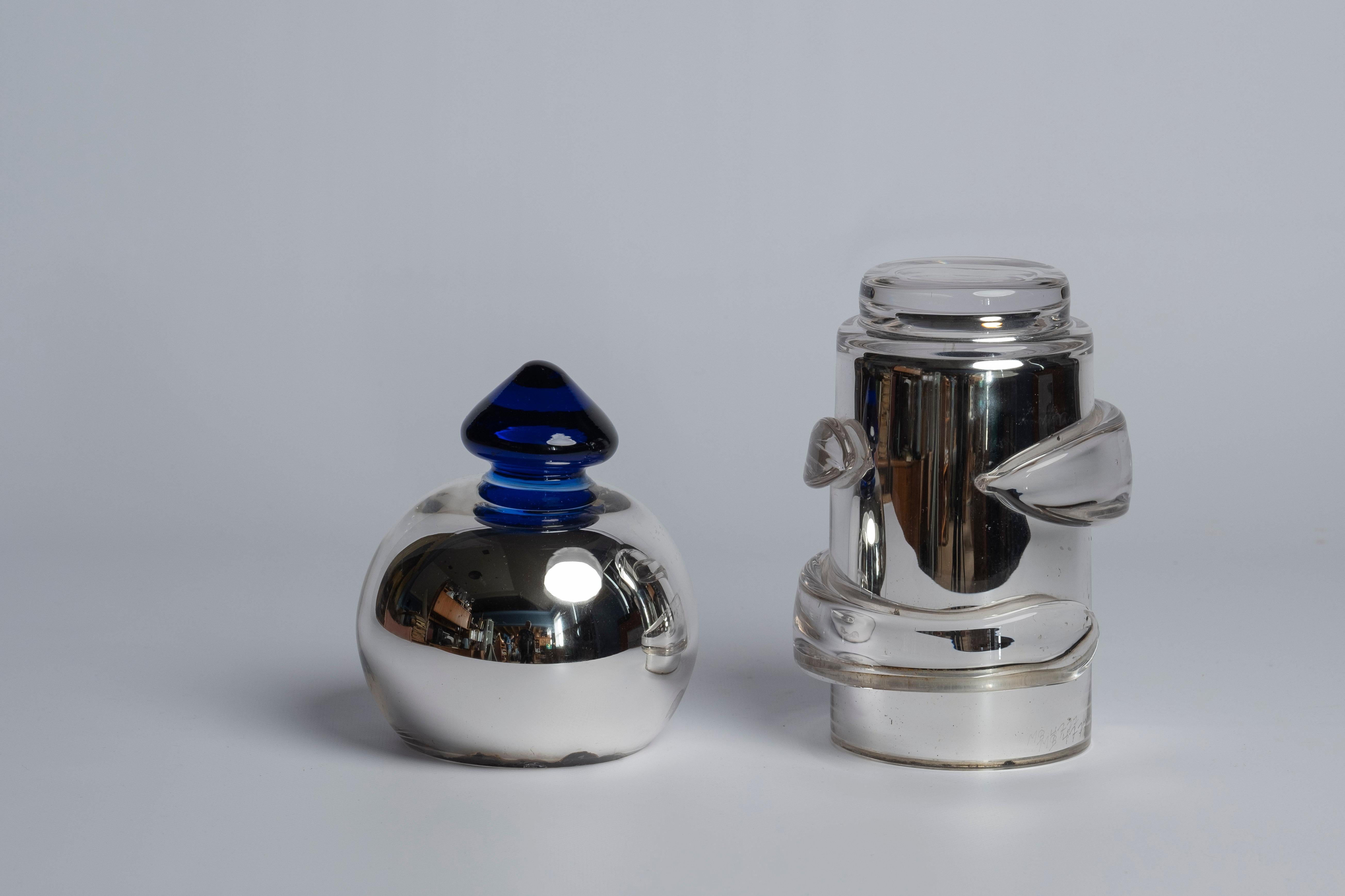 Unique glass sculpture made by Monica Backström for Kosta Boda in the 1990s. Consists of two cylinder shaped glass vessels stacked on each other, both foiled with silver lining on the inside, top piece with a cobolt blue knob. Marked: MB4777 UNIK