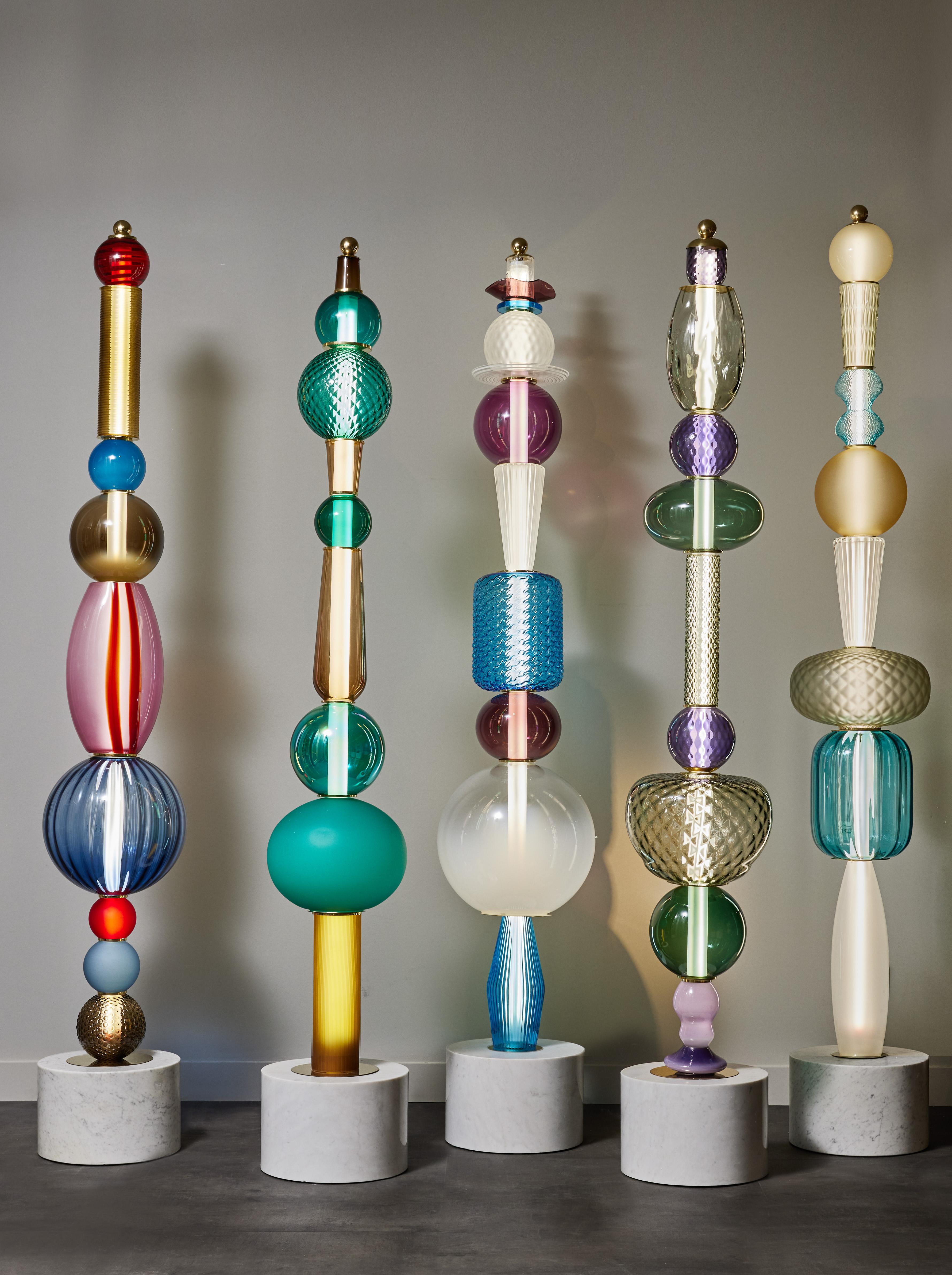 Built like totems, we used a Carrara marble base then stacked different Murano glass parts in various colors and shapes, alternating with some brass discreet elements.

Sold separately, price displayed for one floor lamp.