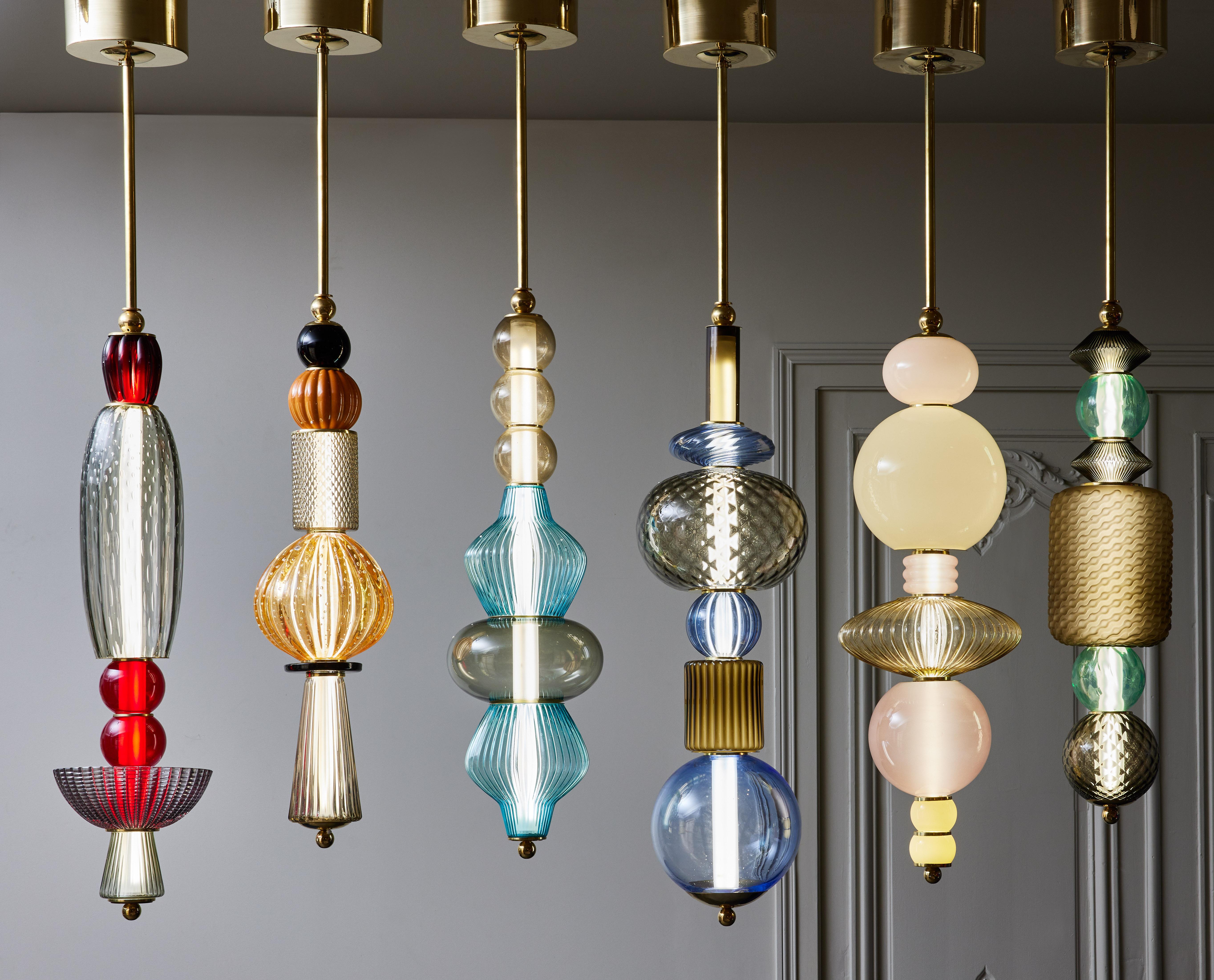 Using the same process as our totem floor lamps, we stacked different Murano glass parts in various colors and shapes, alternating with some brass discreet elements to make these playful suspensions.