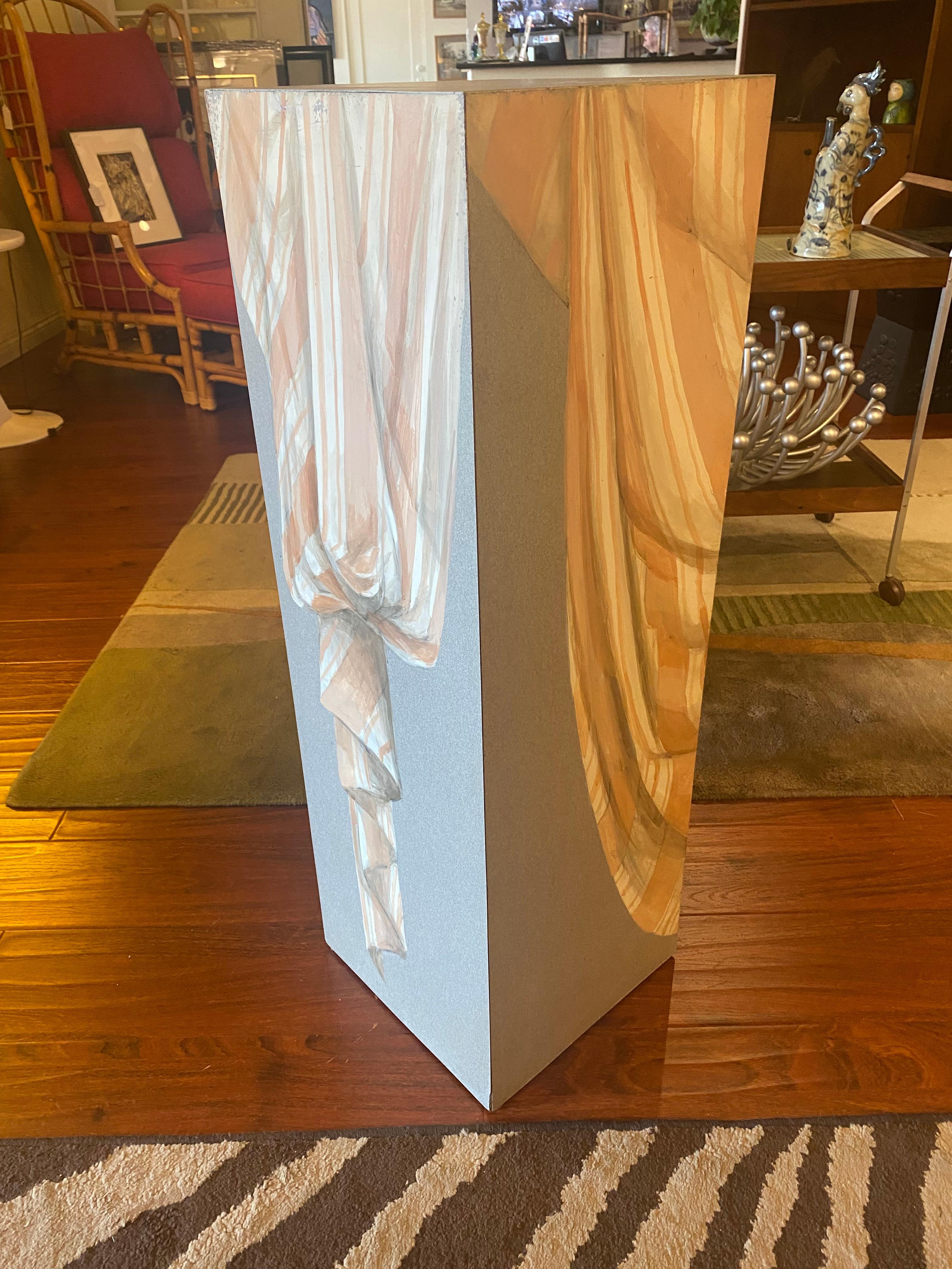 A square pedestal with a unique hand-painted trompe l'œil drapery design. Combining classical illusionistic painting with a modern geometric form, this piece functions as both a display stand and a work of art. Ideal for showcasing sculptures or