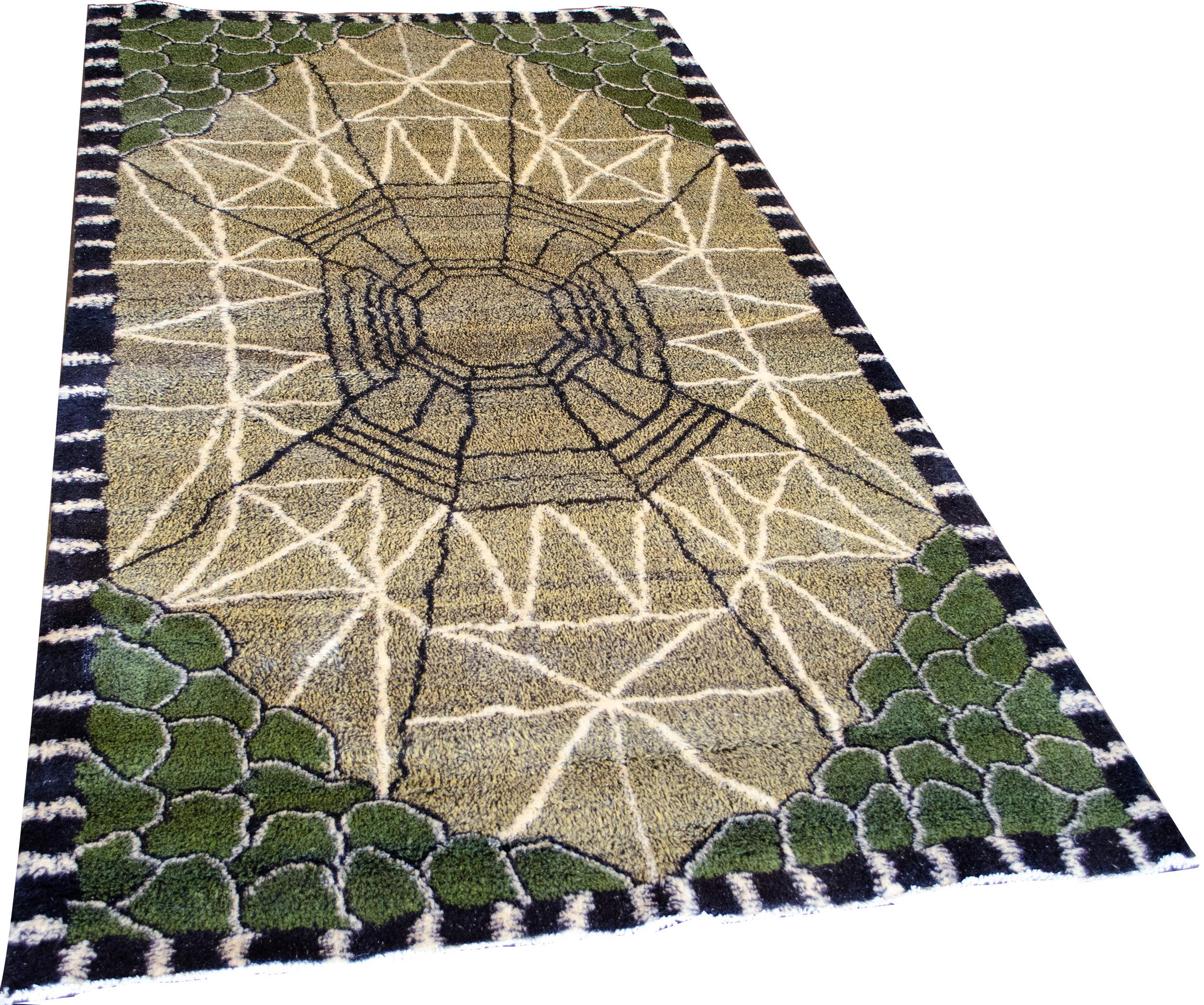 This unique handwoven Turkish deco pile rug has a sandy yellow overall field featuring a pattern reminiscent of an emerald cut gem, olive green pebbled corners, and a black and white perpendicular striped border. 100% wool.