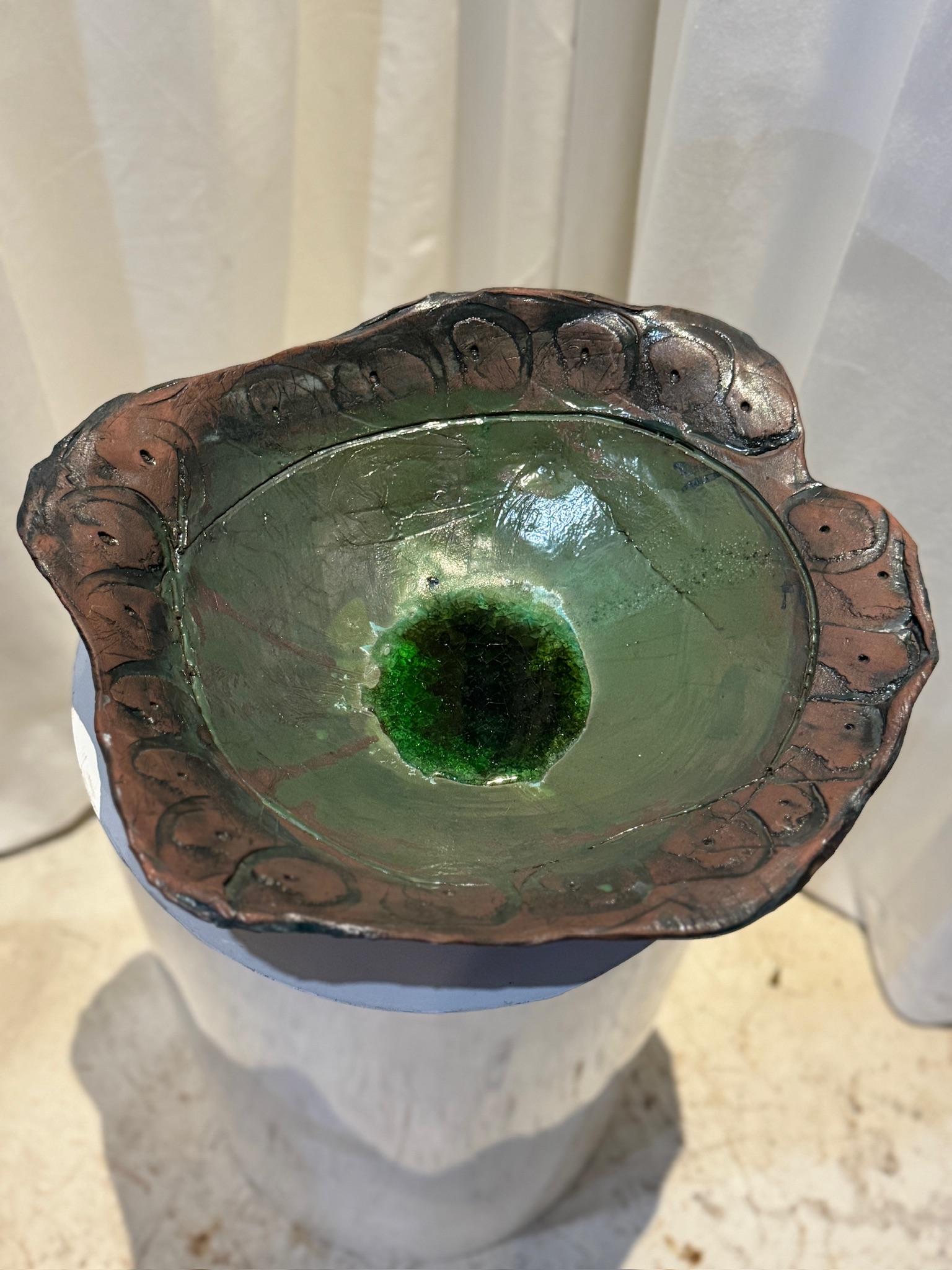 Este impresionante cuenco de cerámica artesanal es una pieza única que combina el encanto rústico con el arte moderno. El cuenco presenta un borde esculpido orgánicamente, de forma libre, que realza su carácter artesanal, convirtiéndolo en un
