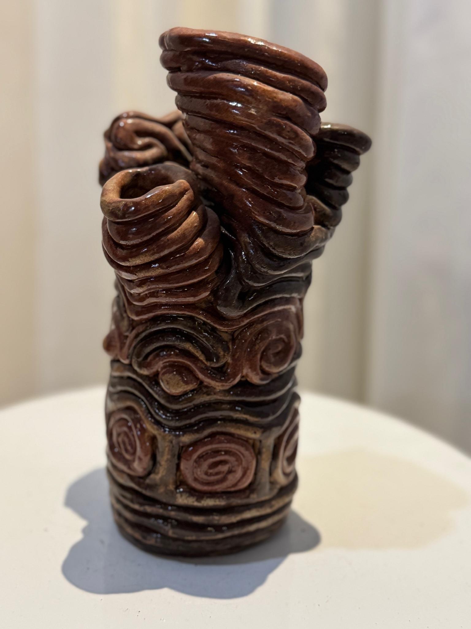 Questo squisito vaso in ceramica lavorato a mano è un esempio lampante della tecnica del vortice d'argilla, un processo intricato in cui le spire di argilla vengono stratificate e modellate a mano per creare una struttura organica e fluida. Il vaso