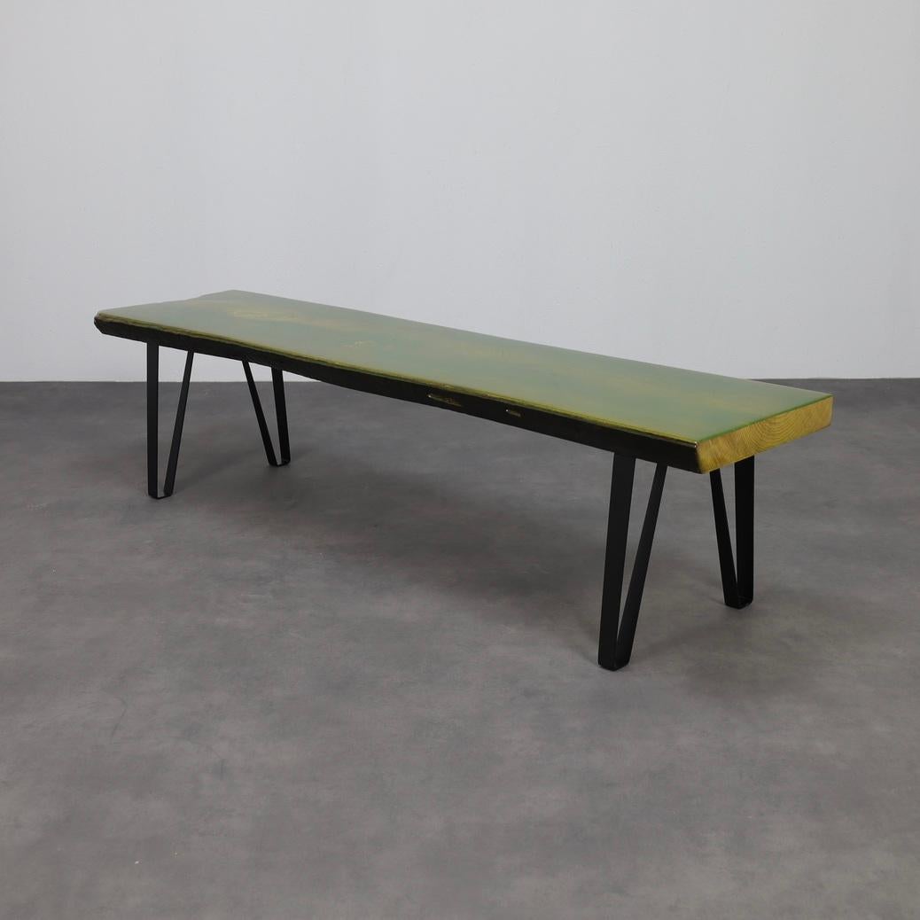 Un llamativo banco único en su especie, obra de un artista desconocido, fabricado con una plancha de madera maciza fundida a la perfección con epoxi verde translúcido que resalta el veteado natural. El borde vivo irregular realza su carácter