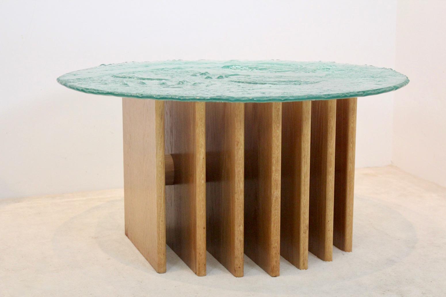 A truly beautiful Brutalist glass top coffee table based on a 7-ribs wooden base. Designed by the German artist Heinz Lilienthal in the 1970s. The wood is very solid and made with oak-veneer and the glass top is very thick and massive and with a