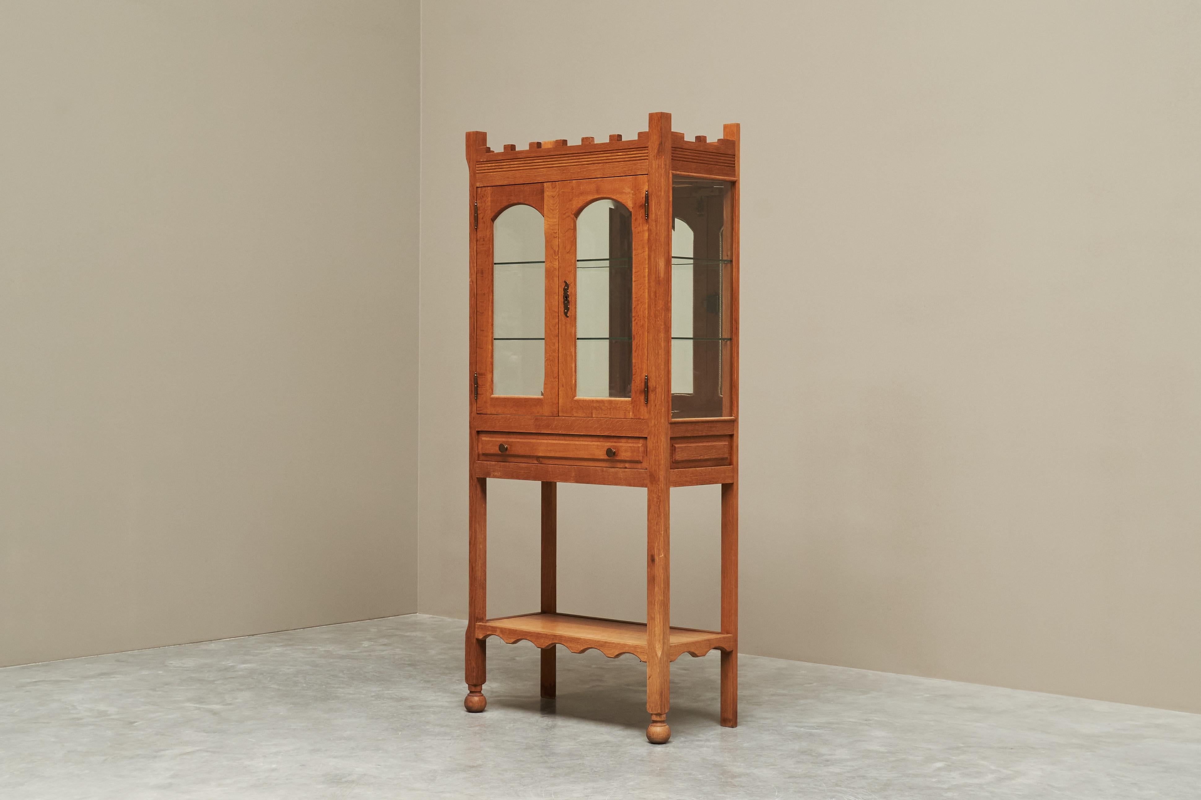 Unique Henning Kjaernulf Style Glazed Display Cabinet in Solid Oak 1970s

This is a truly special glazed display cabinet, made in solid oak somewhere in the 1970s.

Wonderful castle like design with battlements on top, arched windows with bevelled