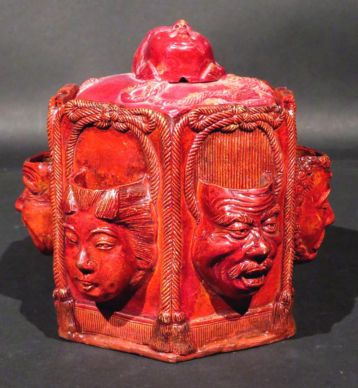 A most unique and highly decorative orientalist inspired tobacco humidor, showing a hexagonal shaped composition body similar to chalk-ware, decorated with match pockets moulded as oriental masks set against tassel framed panels with alternating
