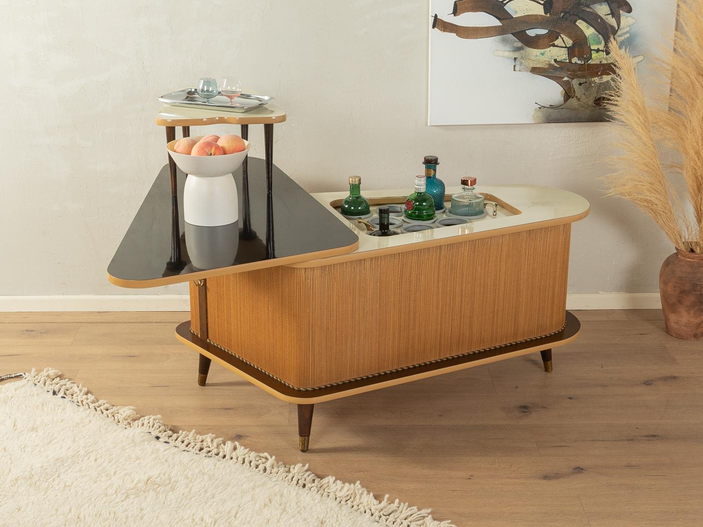 Unique home bar from the 1950s. Corpus with original rattan braid, decorative trims, a bar compartment with glass and bottle holders, a removable side table and slanted feet with brass caps. Surfaces with original Formica coating in black and cream