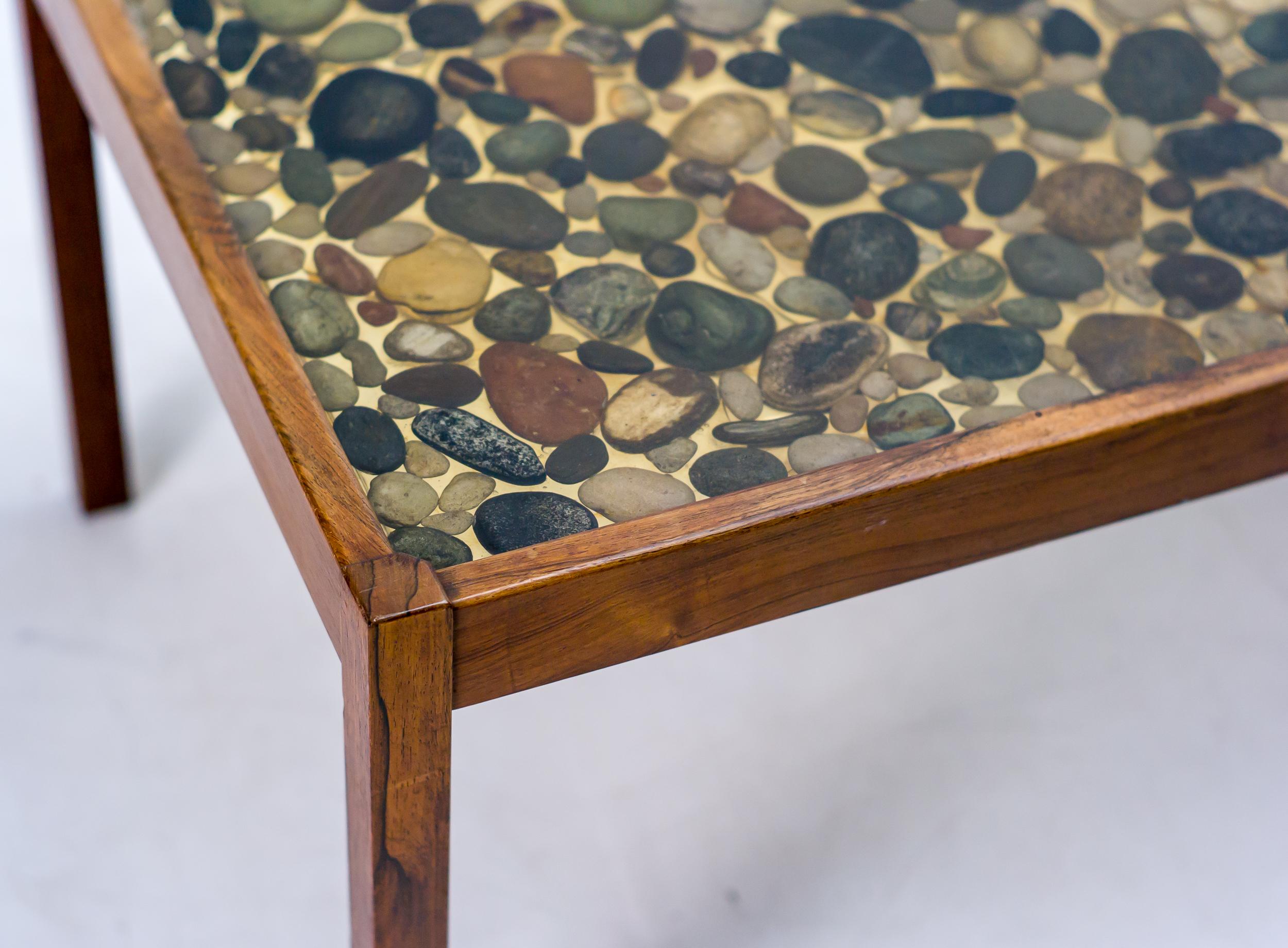 Tavolino in palissandro disegnato da Ib Kofod-Larsen per Seffle Möbelfabrik.
Eccezionale tavolo con piano in poliestere con getto di ciottoli naturali.
Tutto originale, con una leggera usura che conferisce una bella patina.

Ib Kofod-Larsen è nato