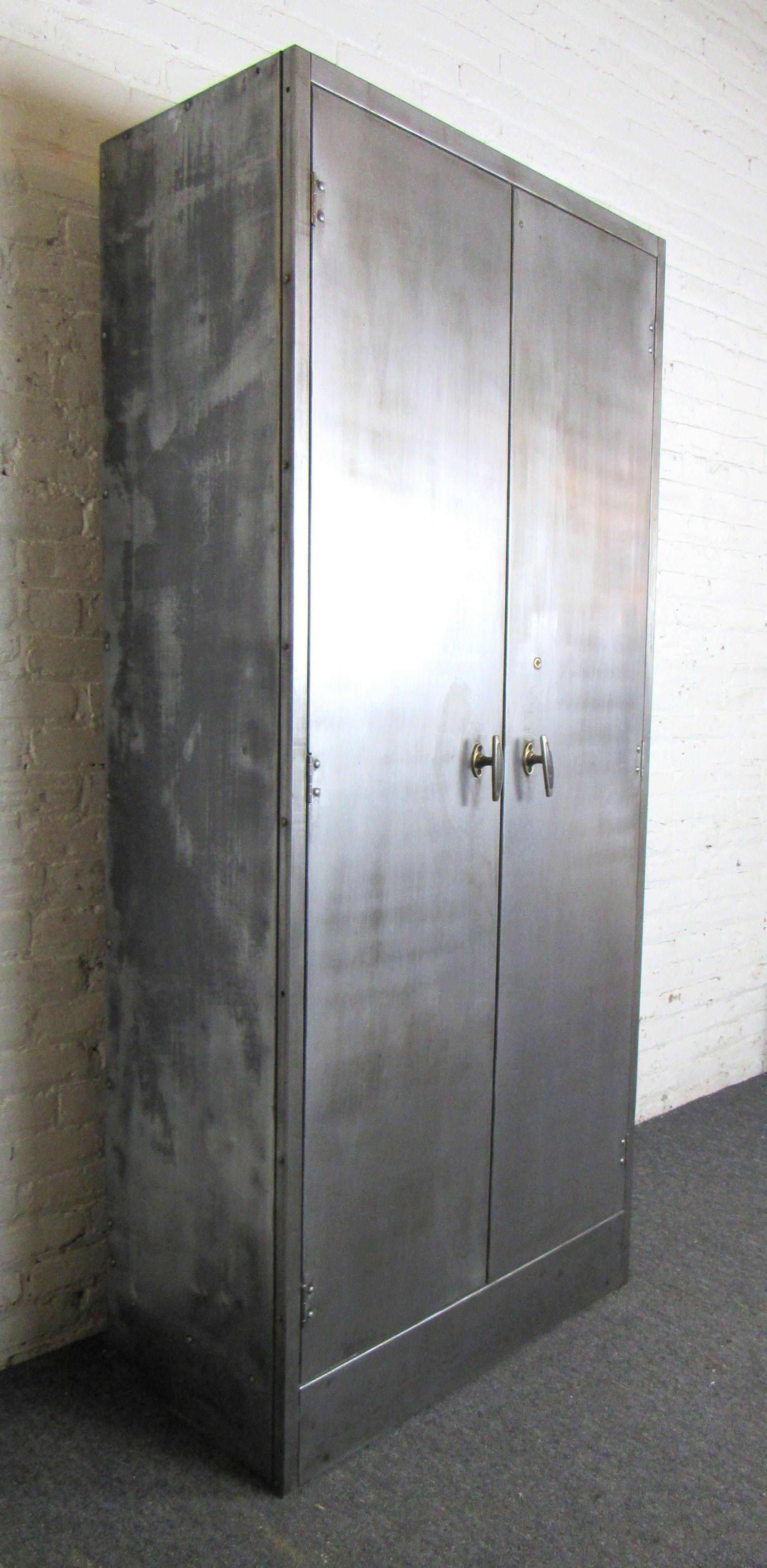 Vintage industrial metal cabinet. The large wardrobe style cabinet features four adjustable shelves that can be reorganized to fit your specific needs. Perfect for any type of storage. Unique sculptural inlaid door pulls and metal patina make this